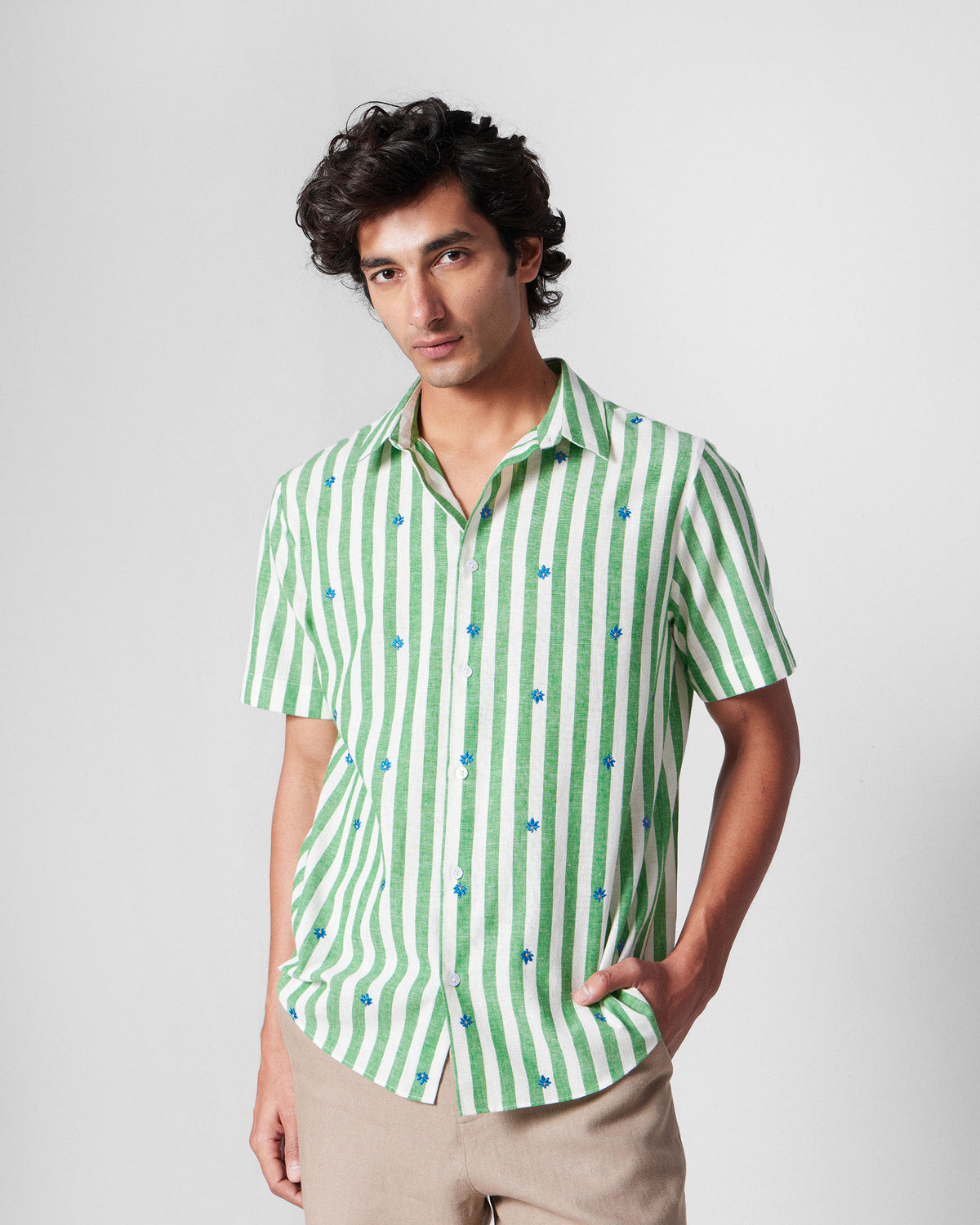 Person wearing a green-and-white striped half-sleeve shirt with blue embroidery.