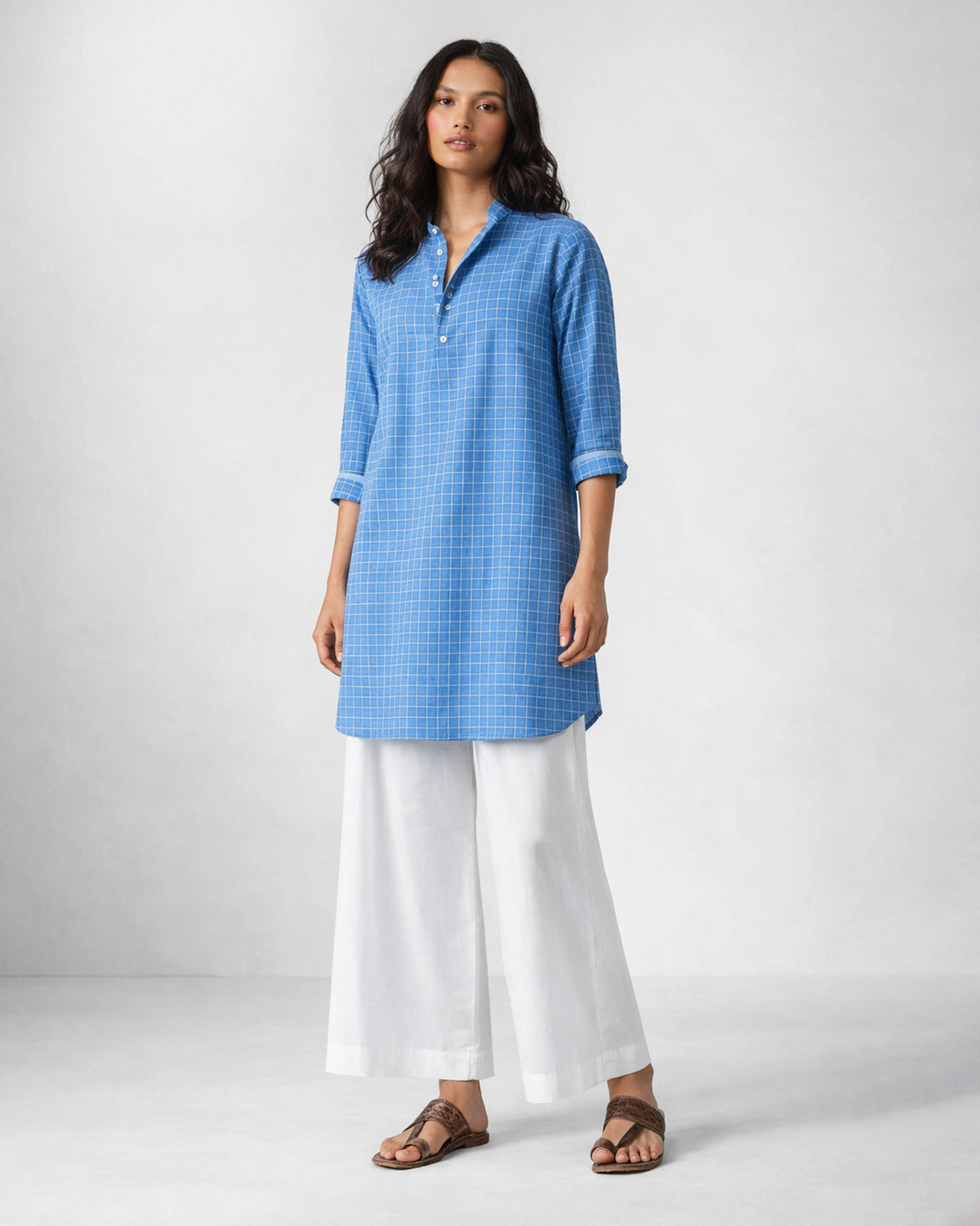 Person wearing a blue checked Nysa kurta with a button placket.
