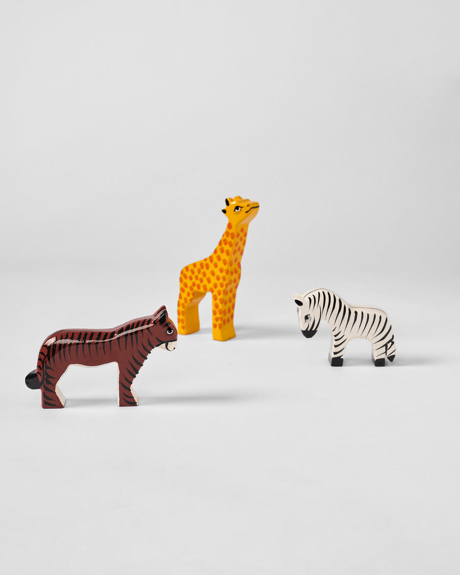 A wooden giraffe, zebra and tiger standing together