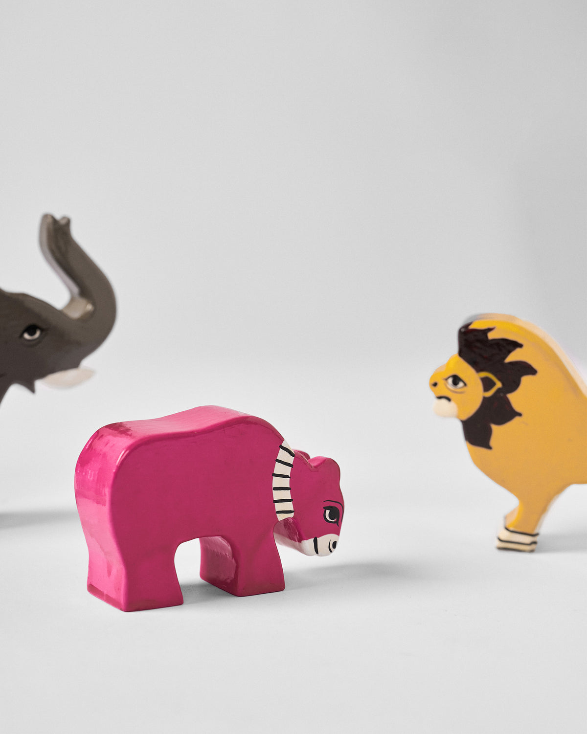 Close-up of the pink Nicojungle figure with an elephant and lion behind it.