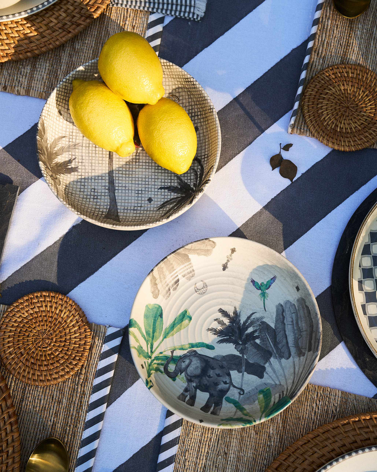 Haathi shallow bowls on a striped cloth, one showing an elephant among green leaves.
