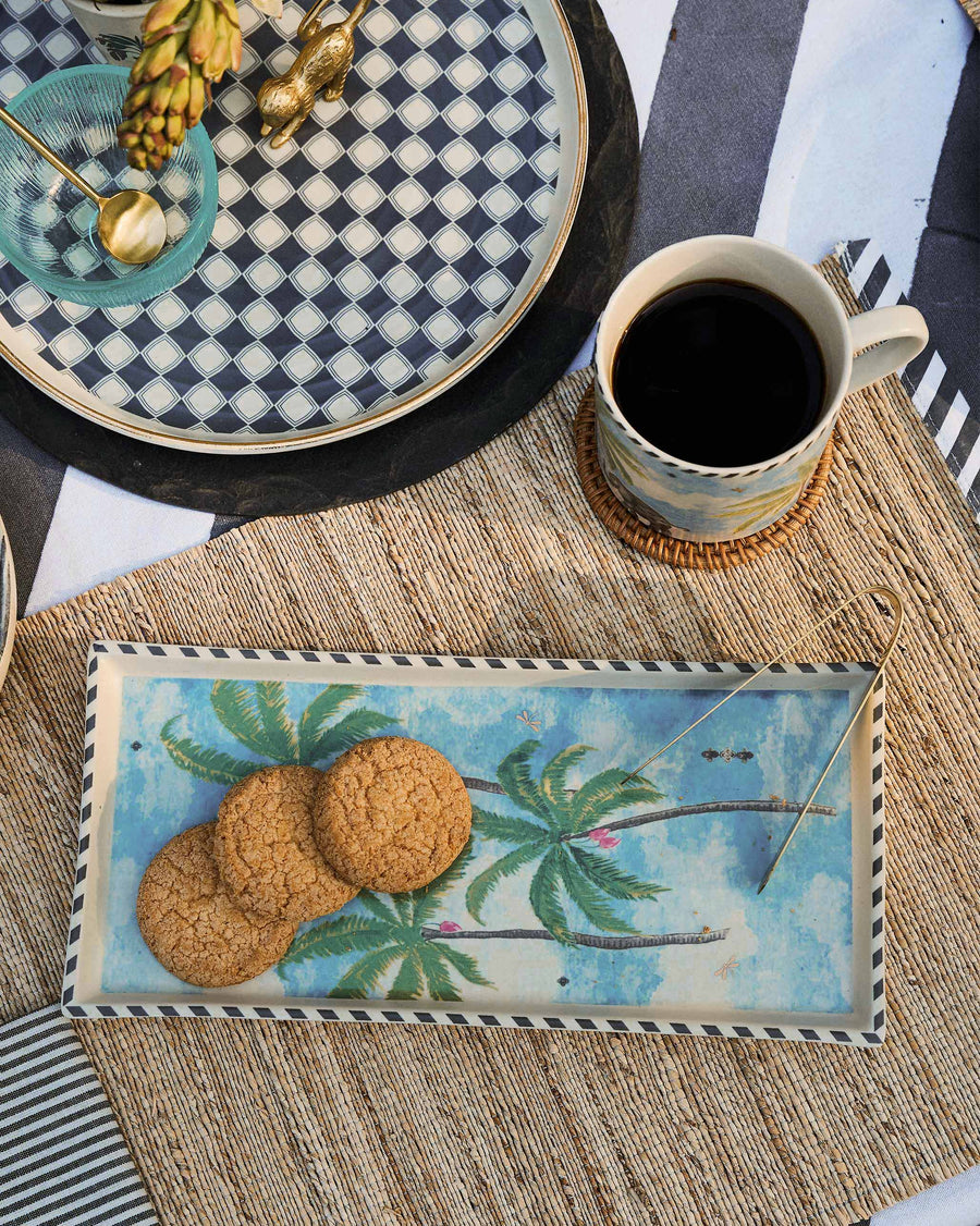 The tray with cookies beside a palm mug.