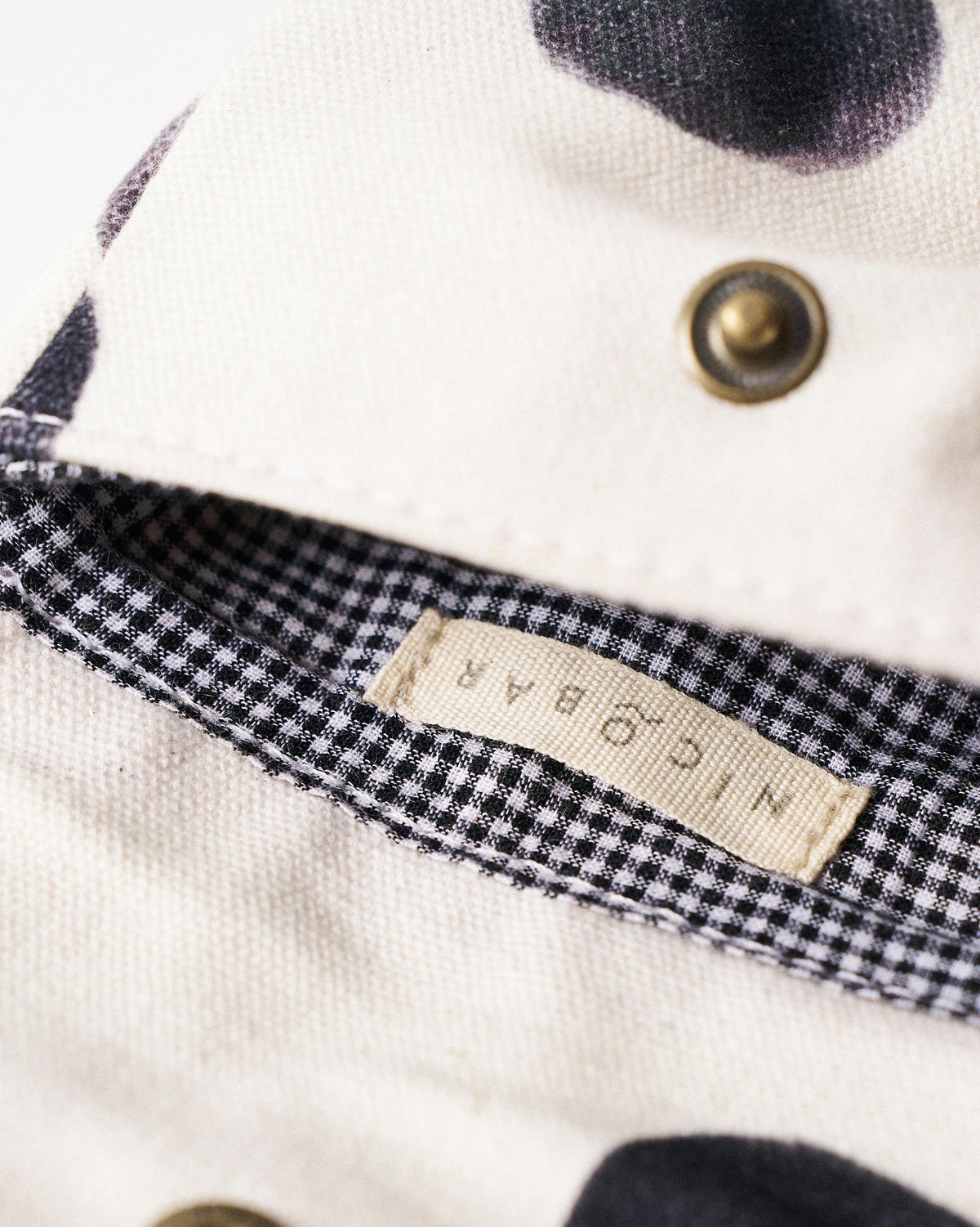 Close-up of a Polka Coin Pouch lining with a Nicobar label and brass snap.