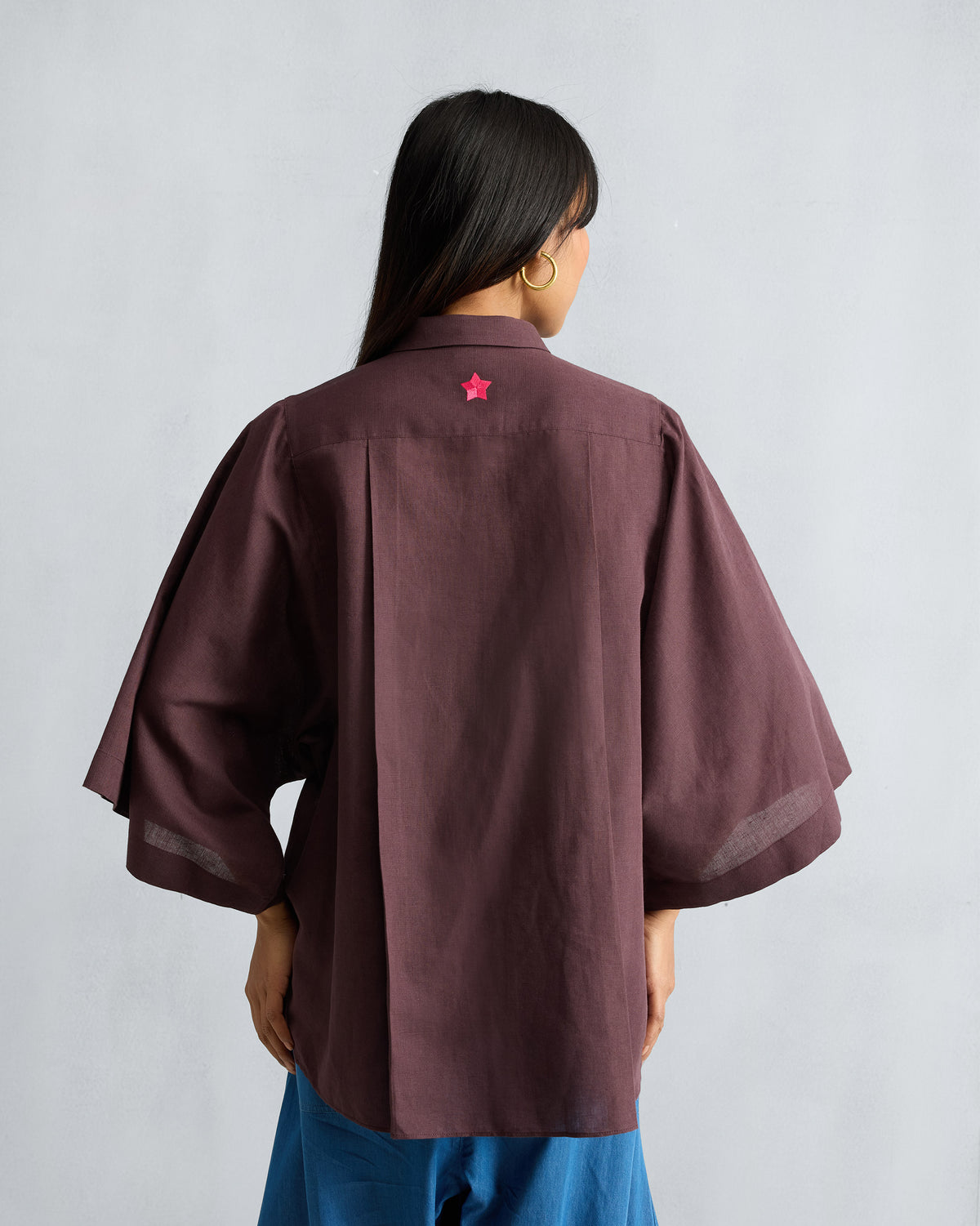 Back of a chocolate plum Drop Armhole Shirt with a pink star embroidery.