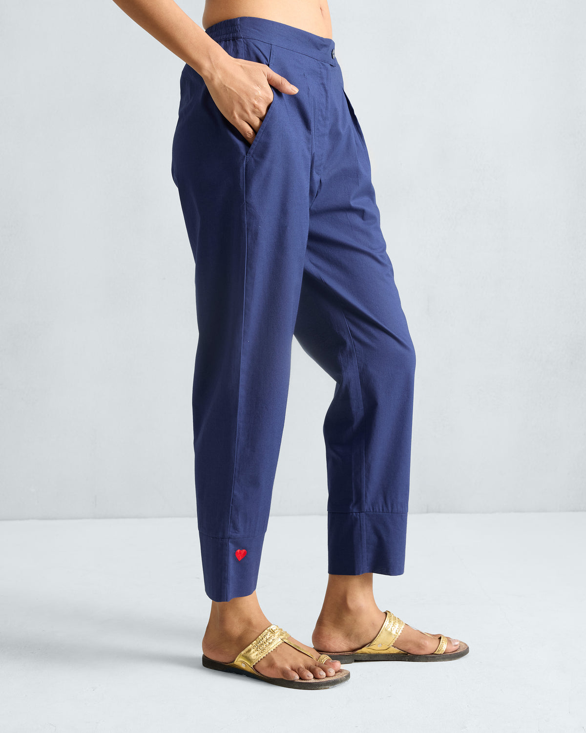 Side view of ink blue narrow pants showing the tapered crop and red heart detail.