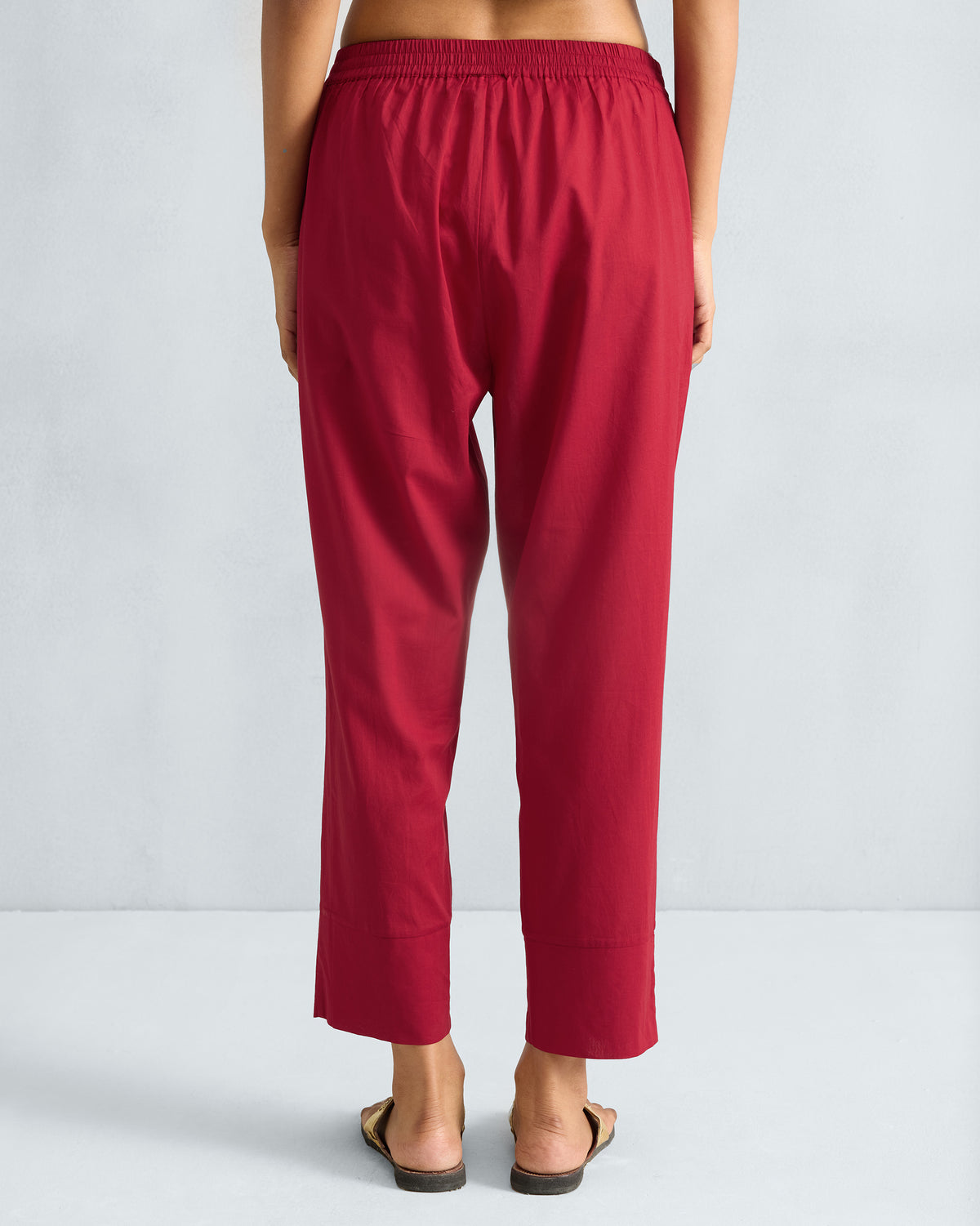 Back of red narrow pants with an elasticated waistband and wide hems.