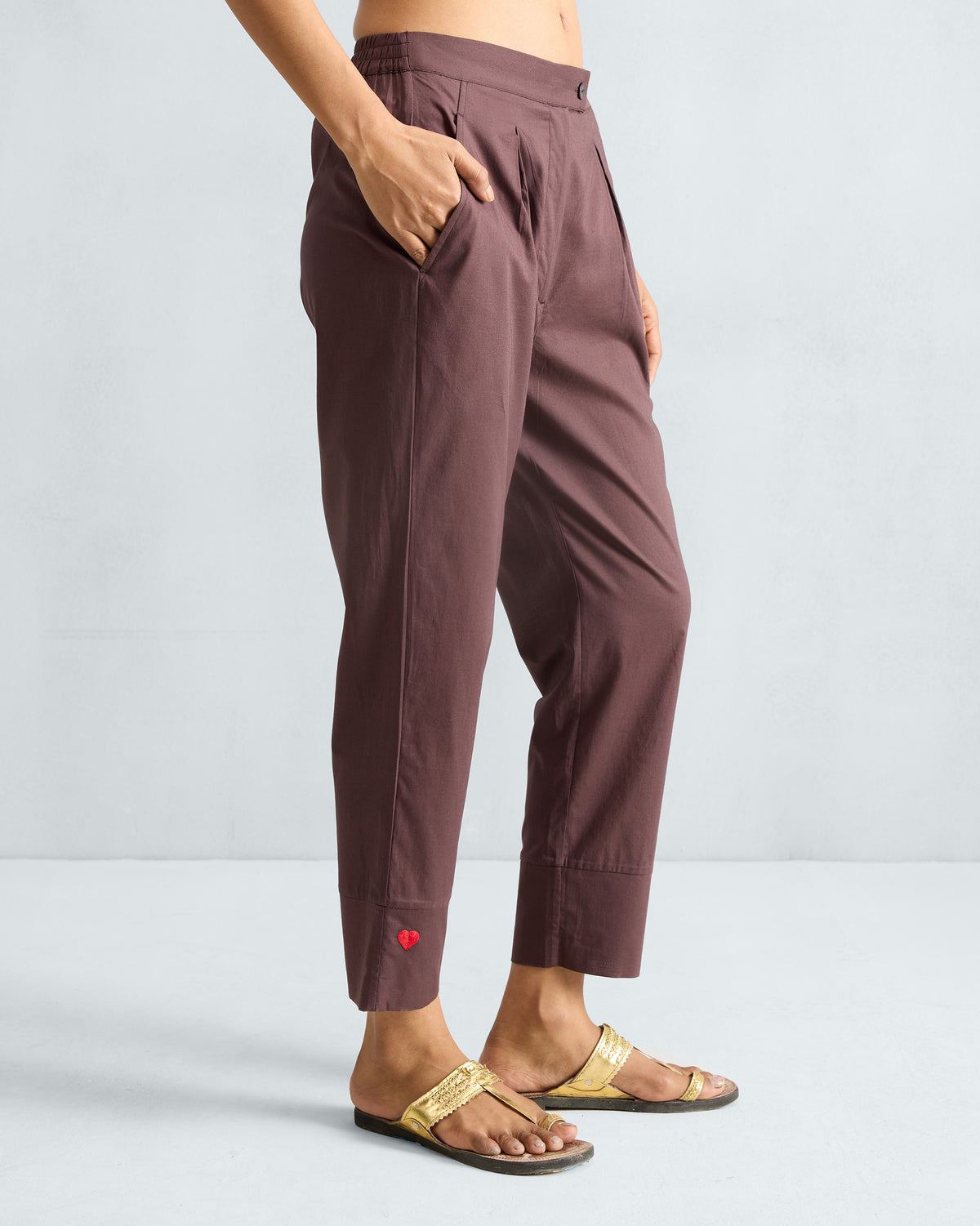 Side view of chocolate plum narrow pants showing the tapered crop and red heart detail.