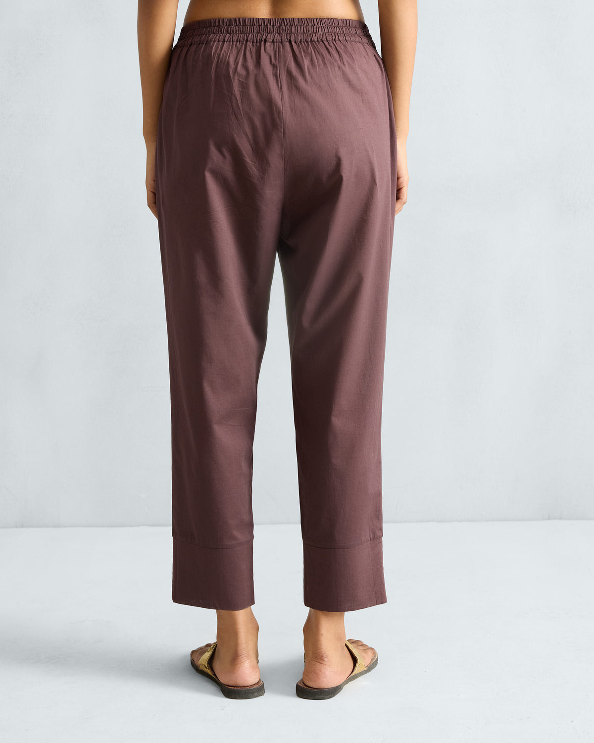 Back of chocolate plum narrow pants with an elasticated waistband and wide hems.