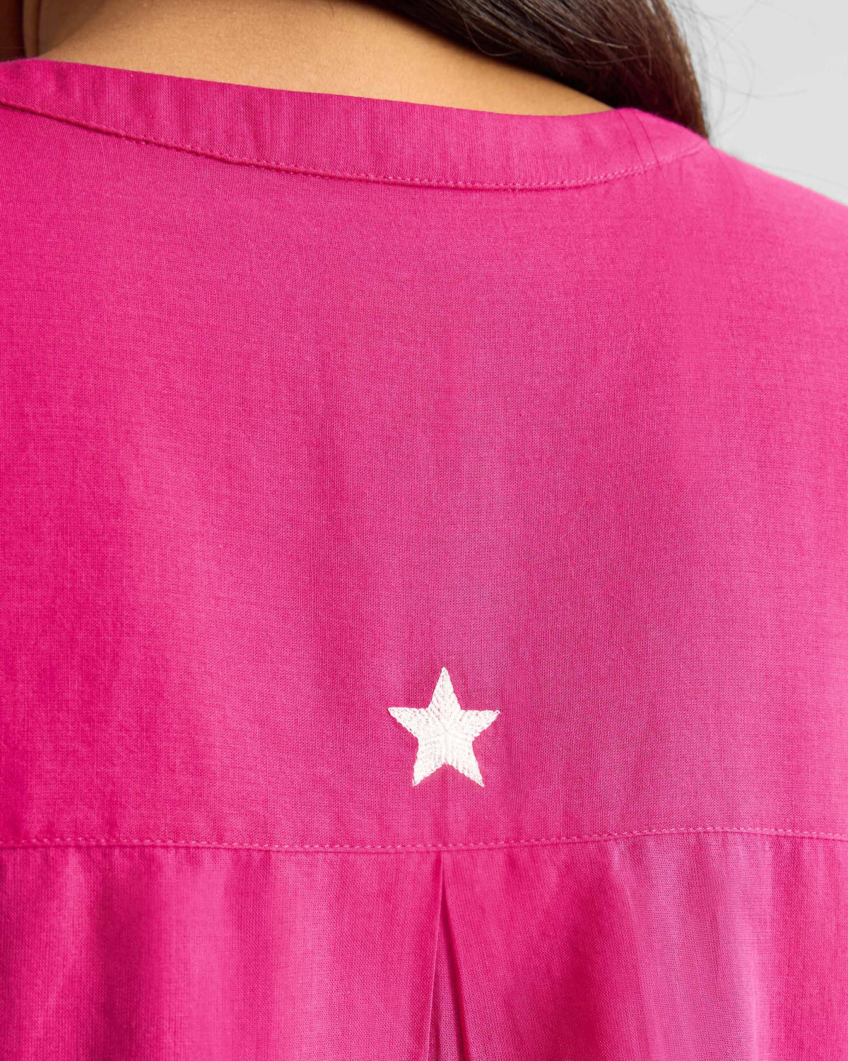 Close-up of a white star on a fuchsia Lazy Sunday tunic.