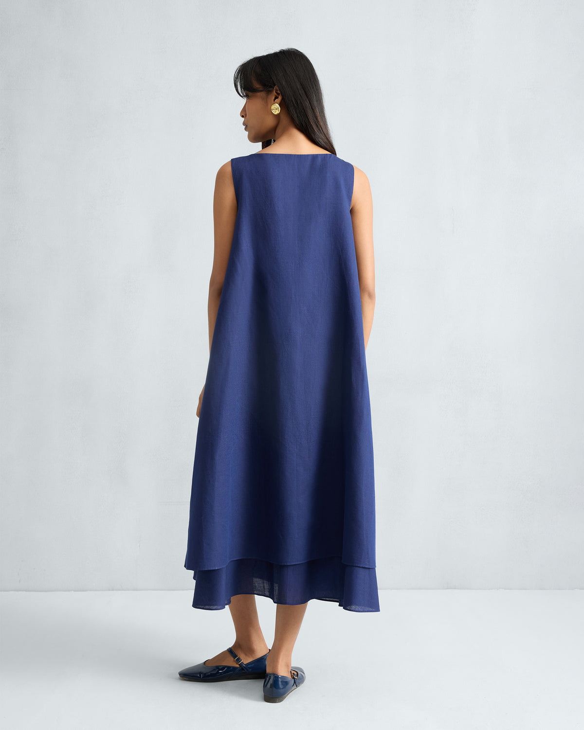 Back of an ink blue Double Layer Dress with a tiered midi hem.