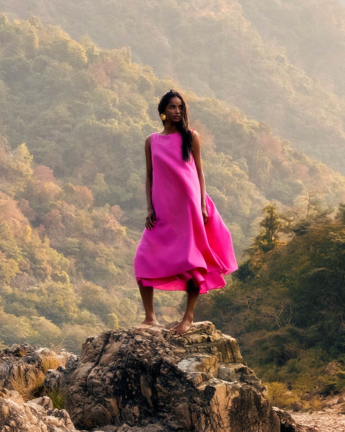 Person wearing a long fuchsia sleeveless dress.
