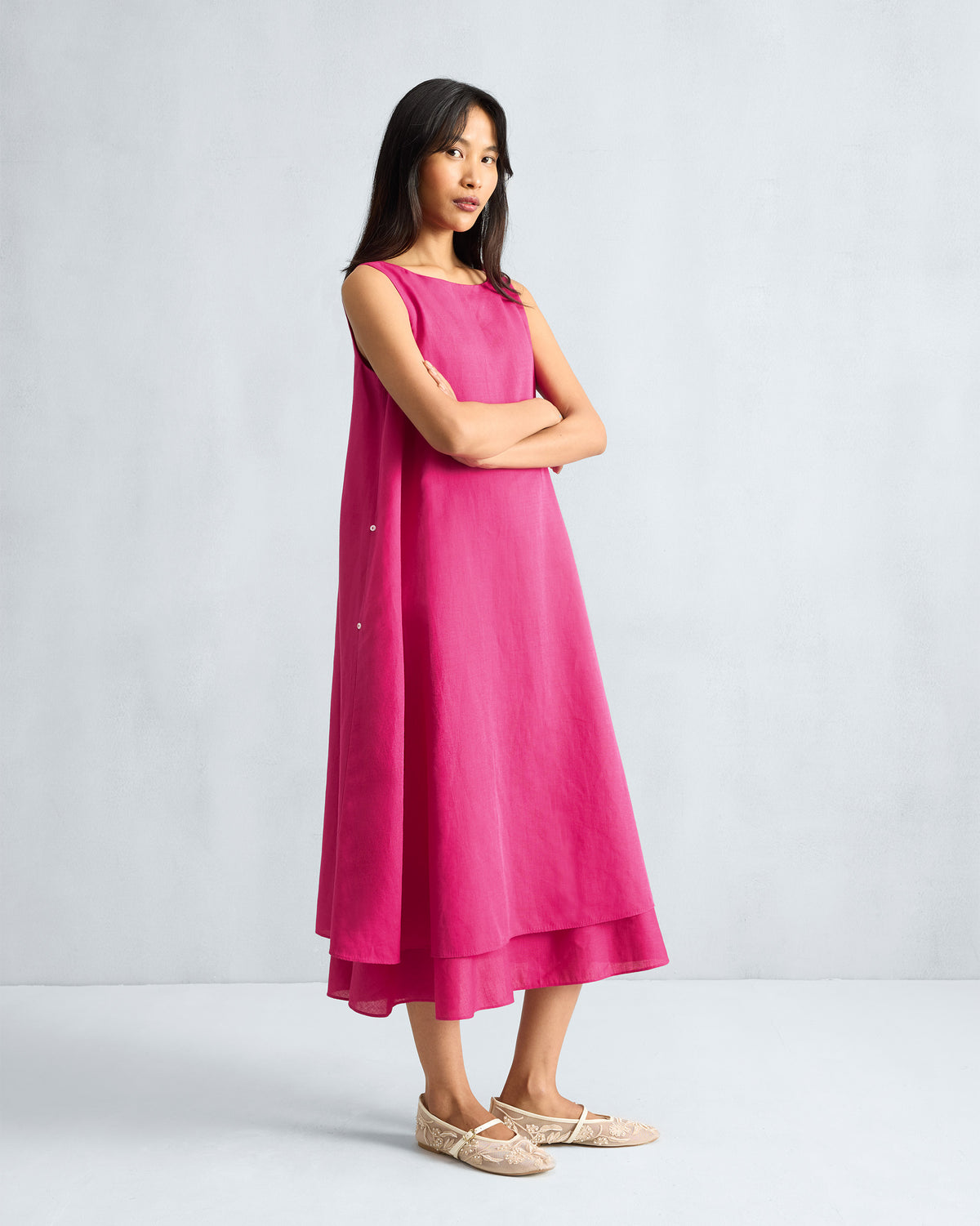 Person wearing a fuchsia sleeveless midi dress showing side buttons.