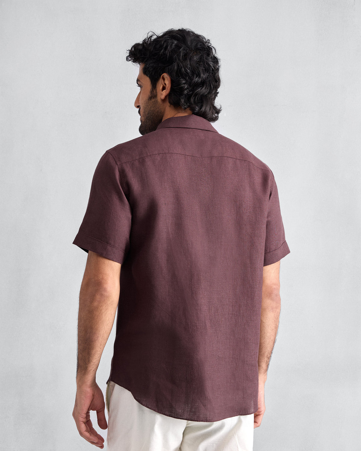 Back of a chocolate plum half-sleeve shirt worn by a person.