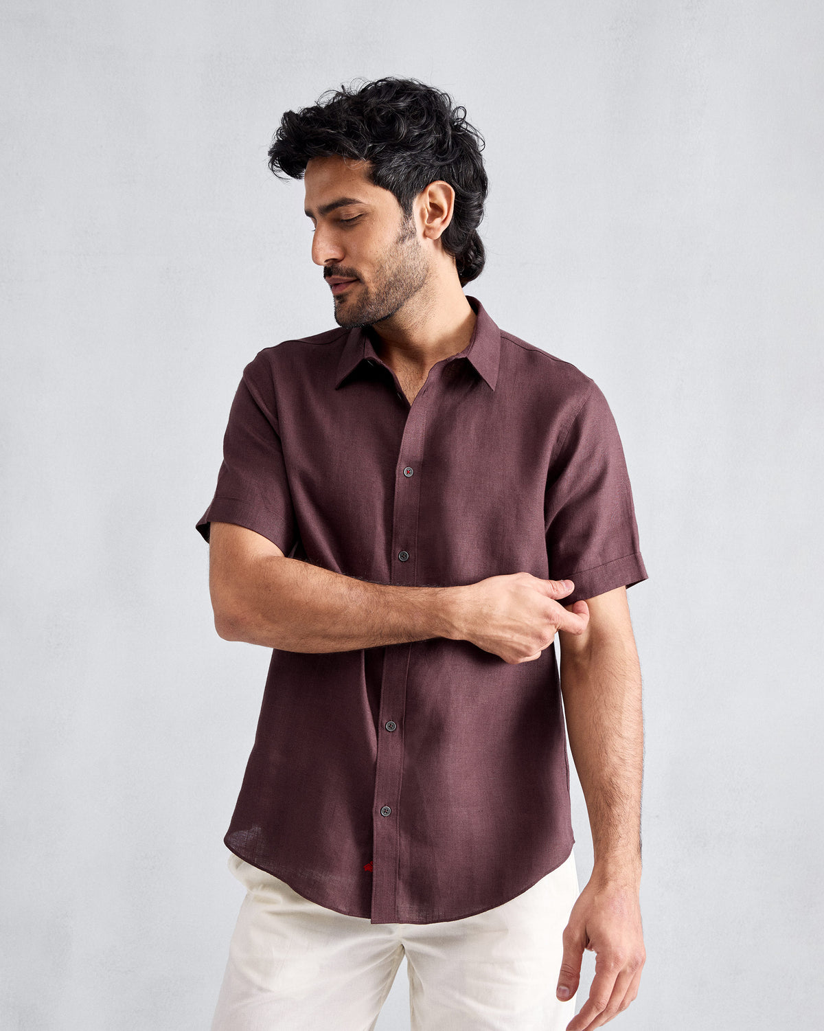 Person wearing a chocolate plum half-sleeve shirt with a curved hem.