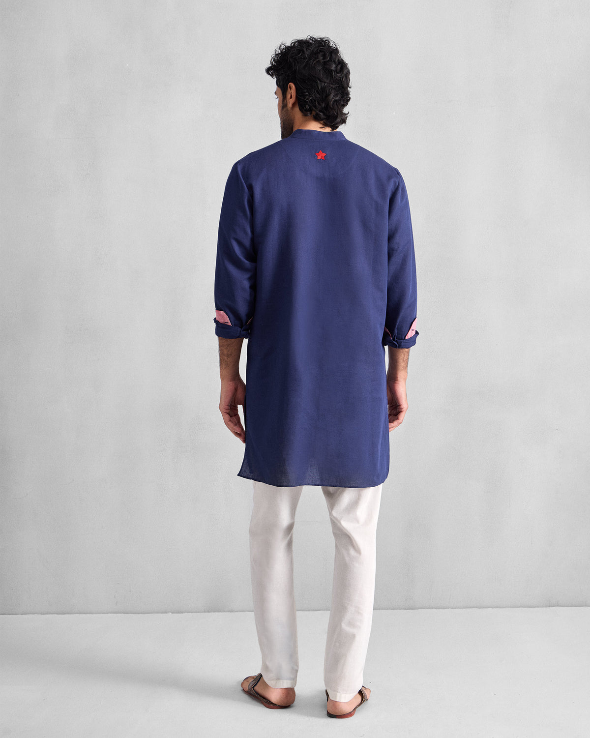 Back of an ink blue Chandni Chowk Kurta with a red embroidered star below the collar.