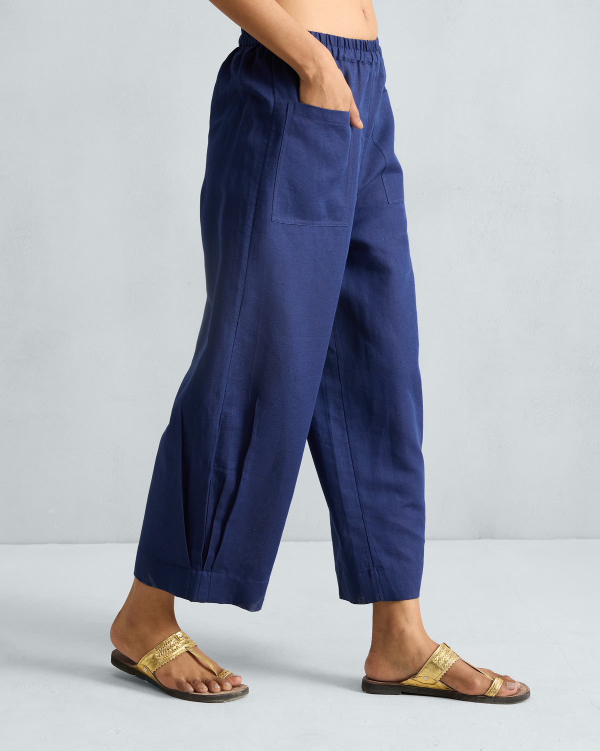 Side view of ink blue Serene pants showing wide legs and pleated hem detail.