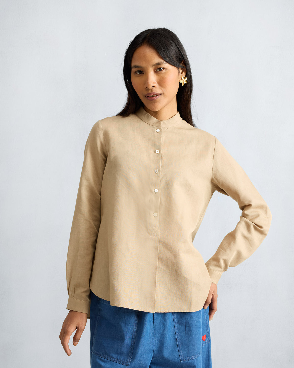 Front of a beige mandarin collar top with long sleeves and a curved hem.