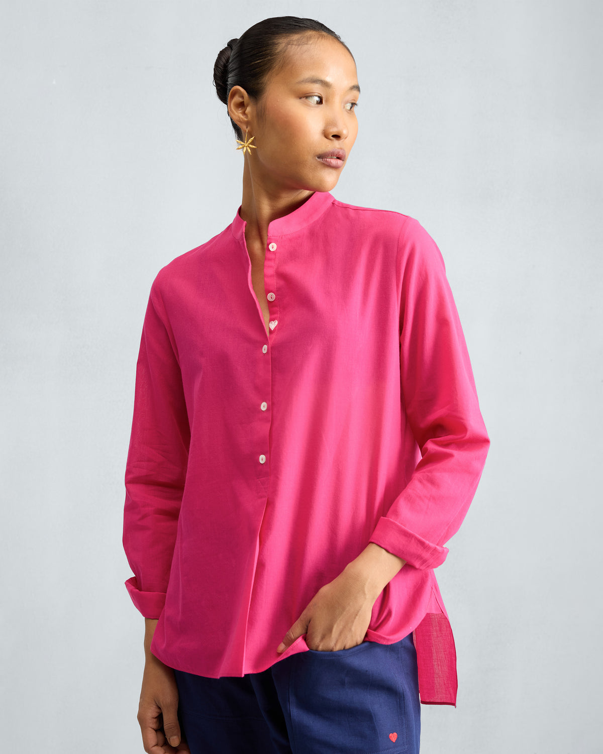 Person wearing a fuchsia mandarin collar top.