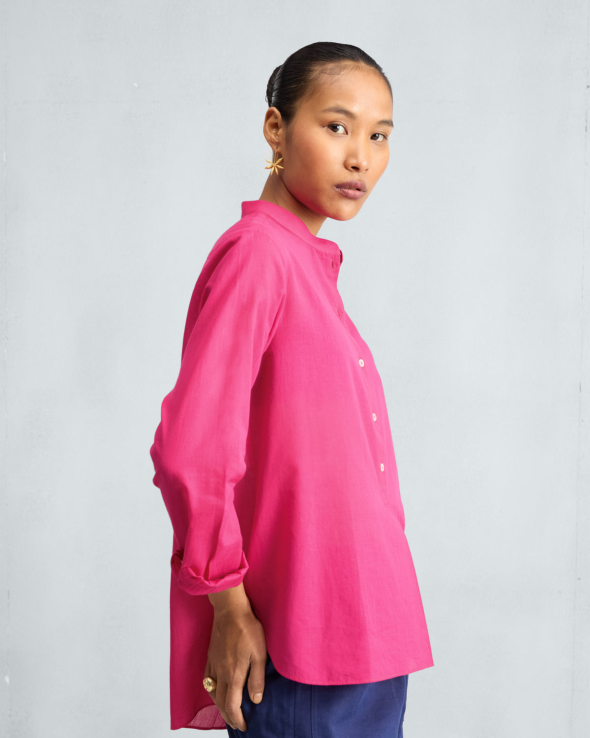Side view of a fuchsia mandarin collar top worn by a person.