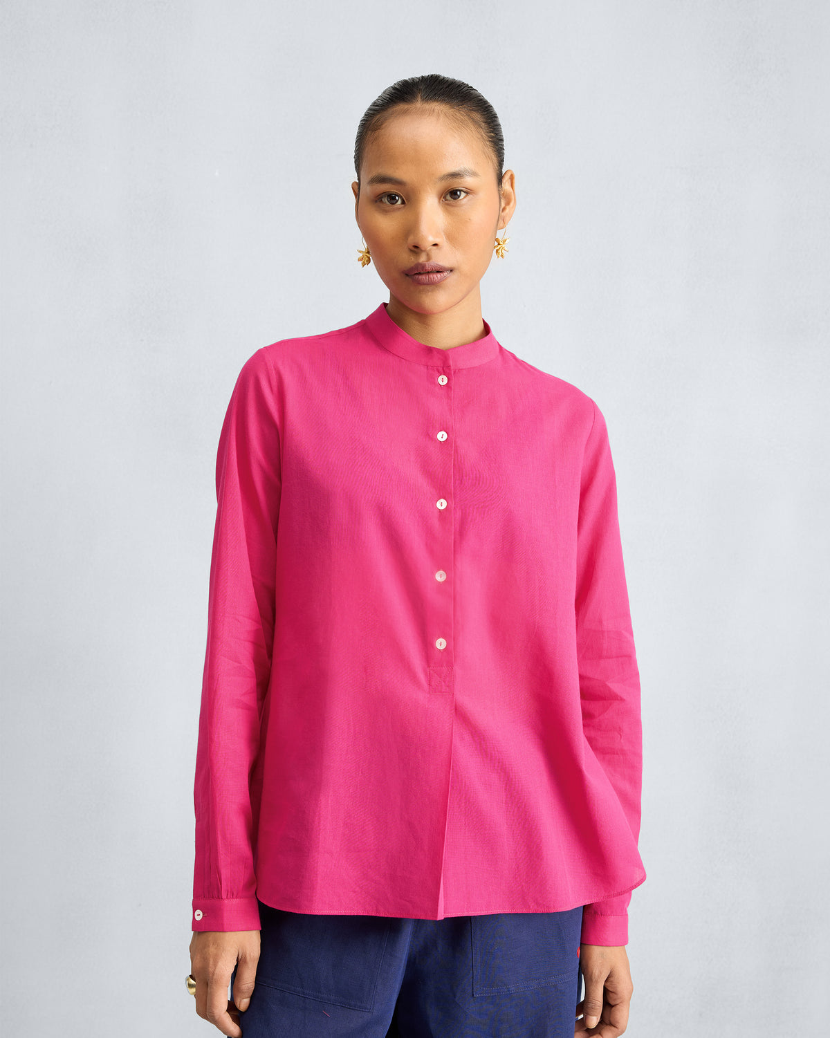 Person wearing a fuchsia mandarin collar top.