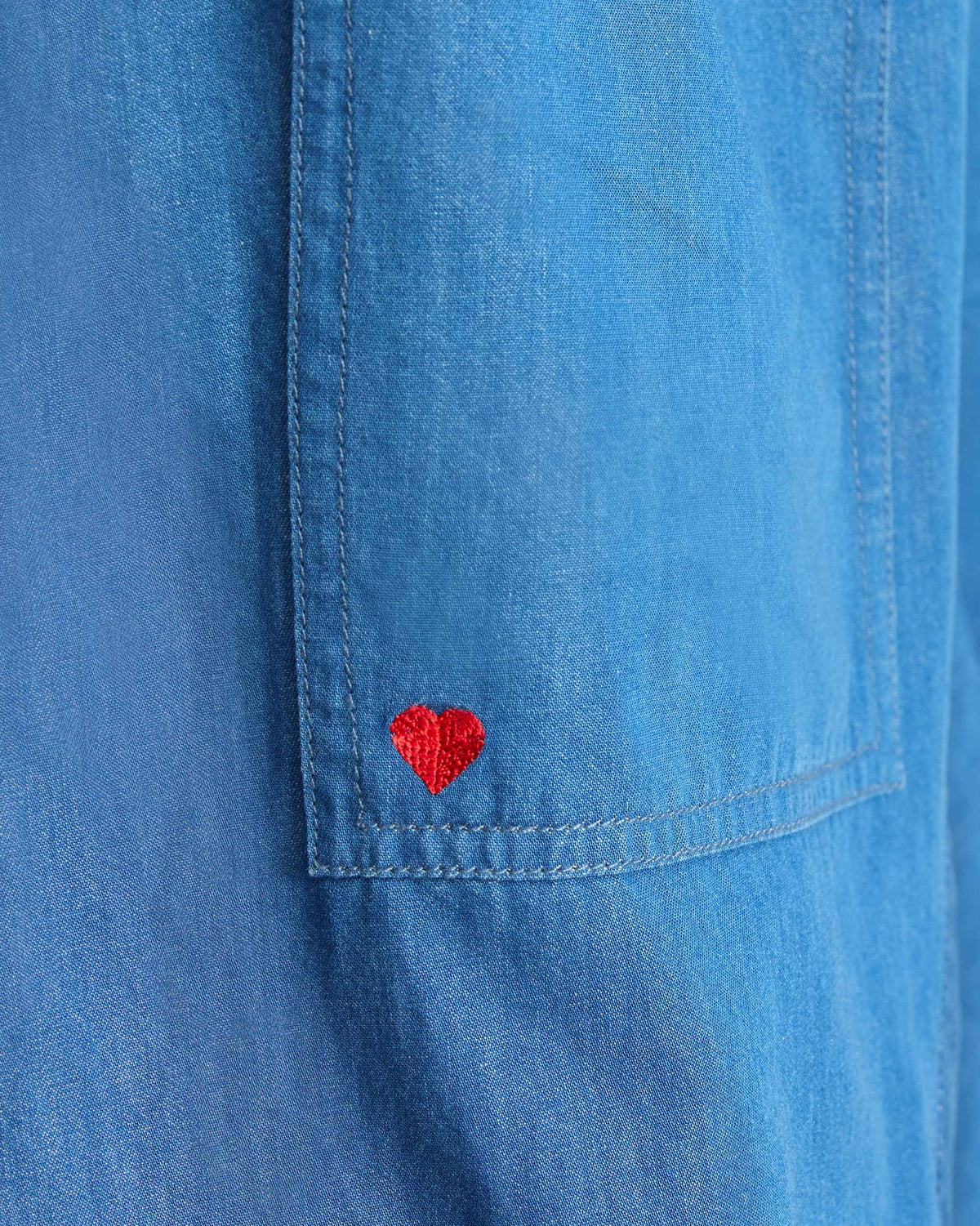 Close-up of a red heart on the pocket of denim Yoka Trousers.