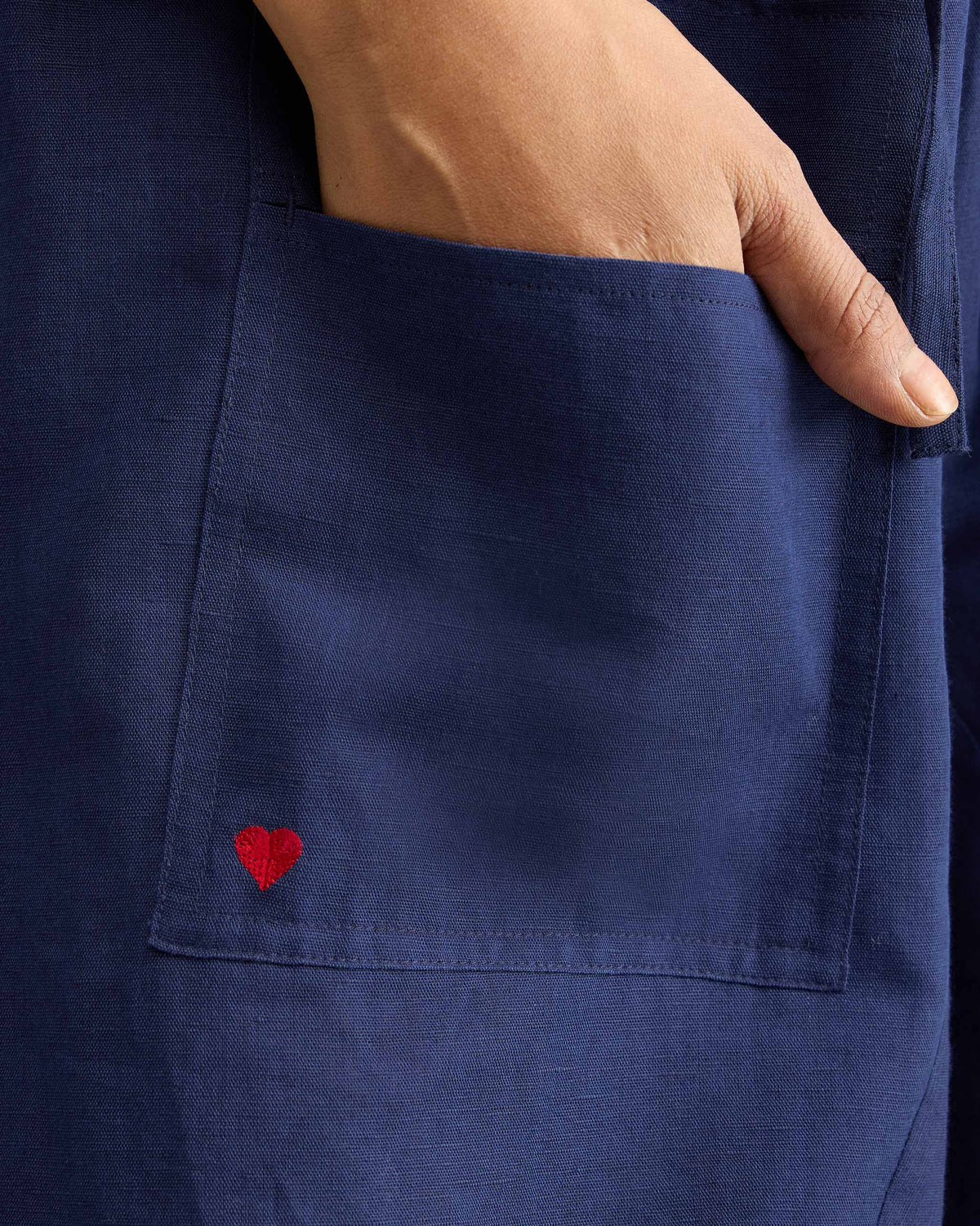 Close-up of a red heart on the pocket of ink blue Yoka Trousers.