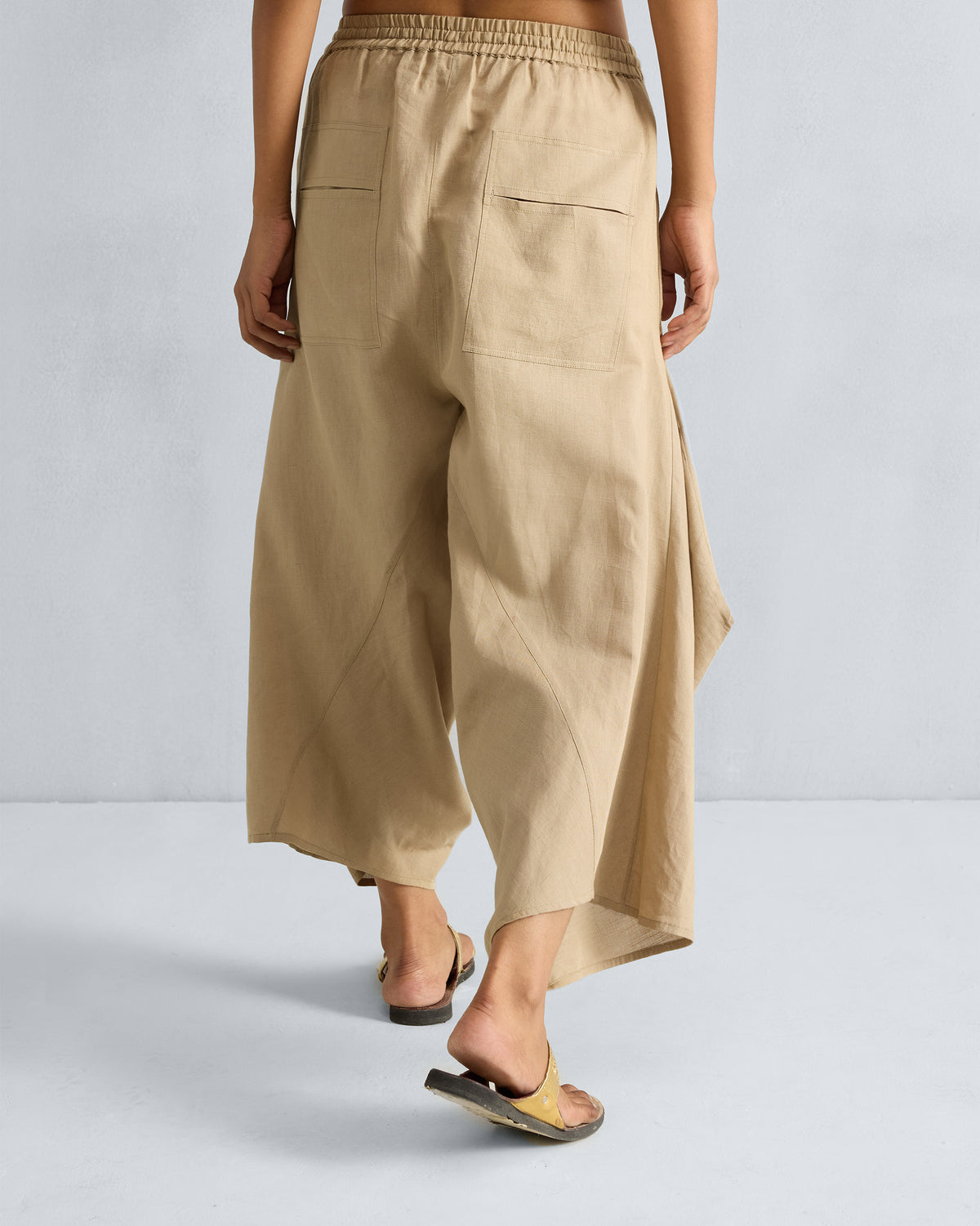 Back of beige Yoka Trousers with patch pockets worn by a person.