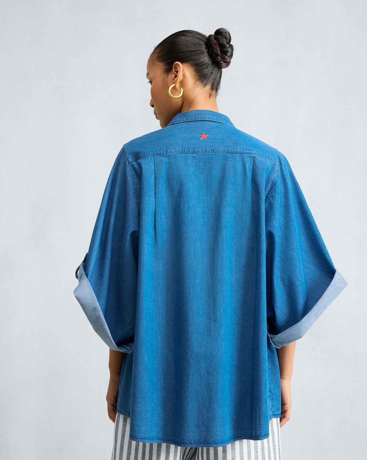 Back of a blue denim shirt with a small red star on the yoke.