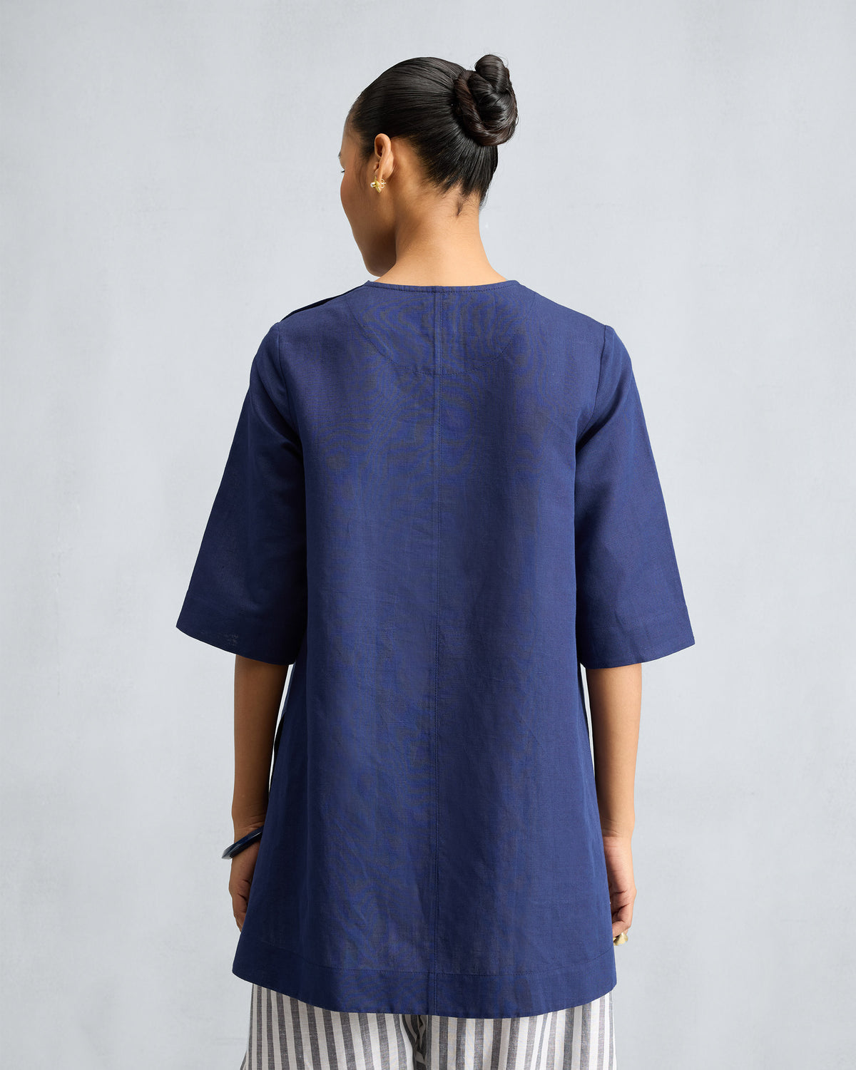 Back of an ink blue High Slit Top with a center seam and wide sleeves.