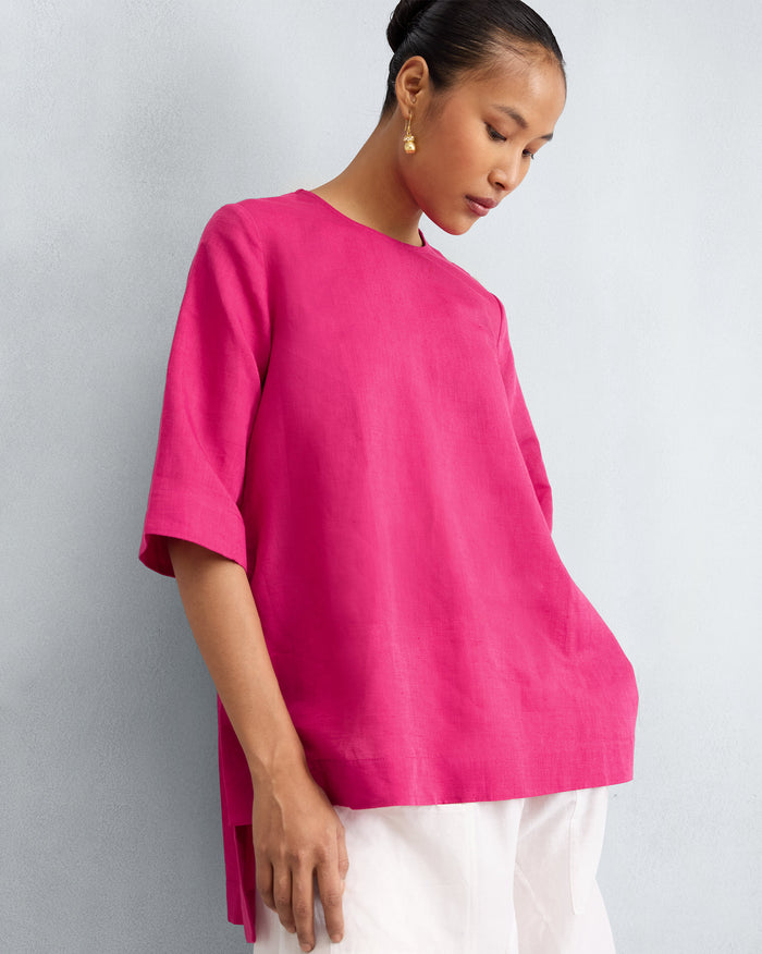 Person wearing a fuchsia loose top with high side slits.