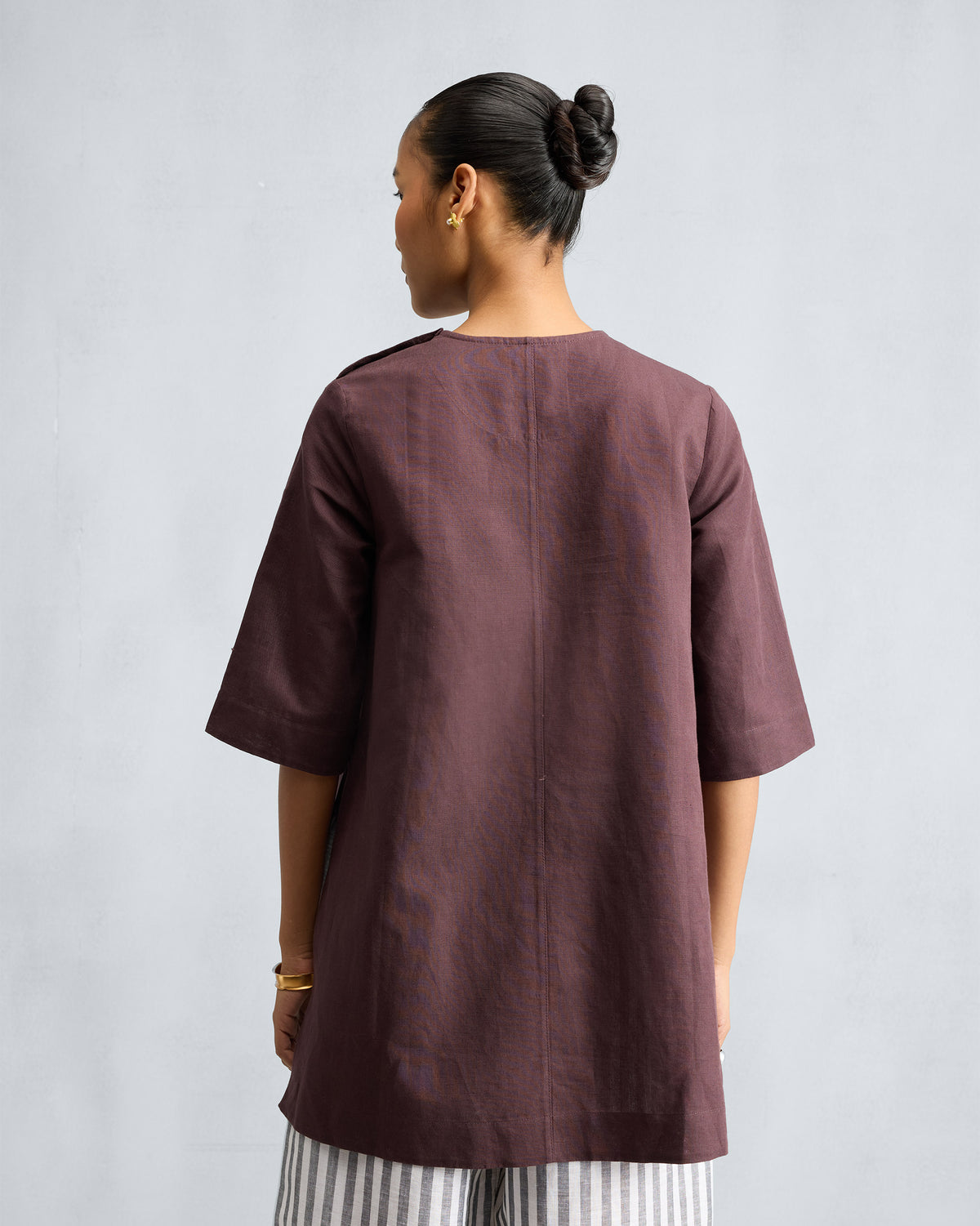 Back of a chocolate plum High Slit Top with a center seam.