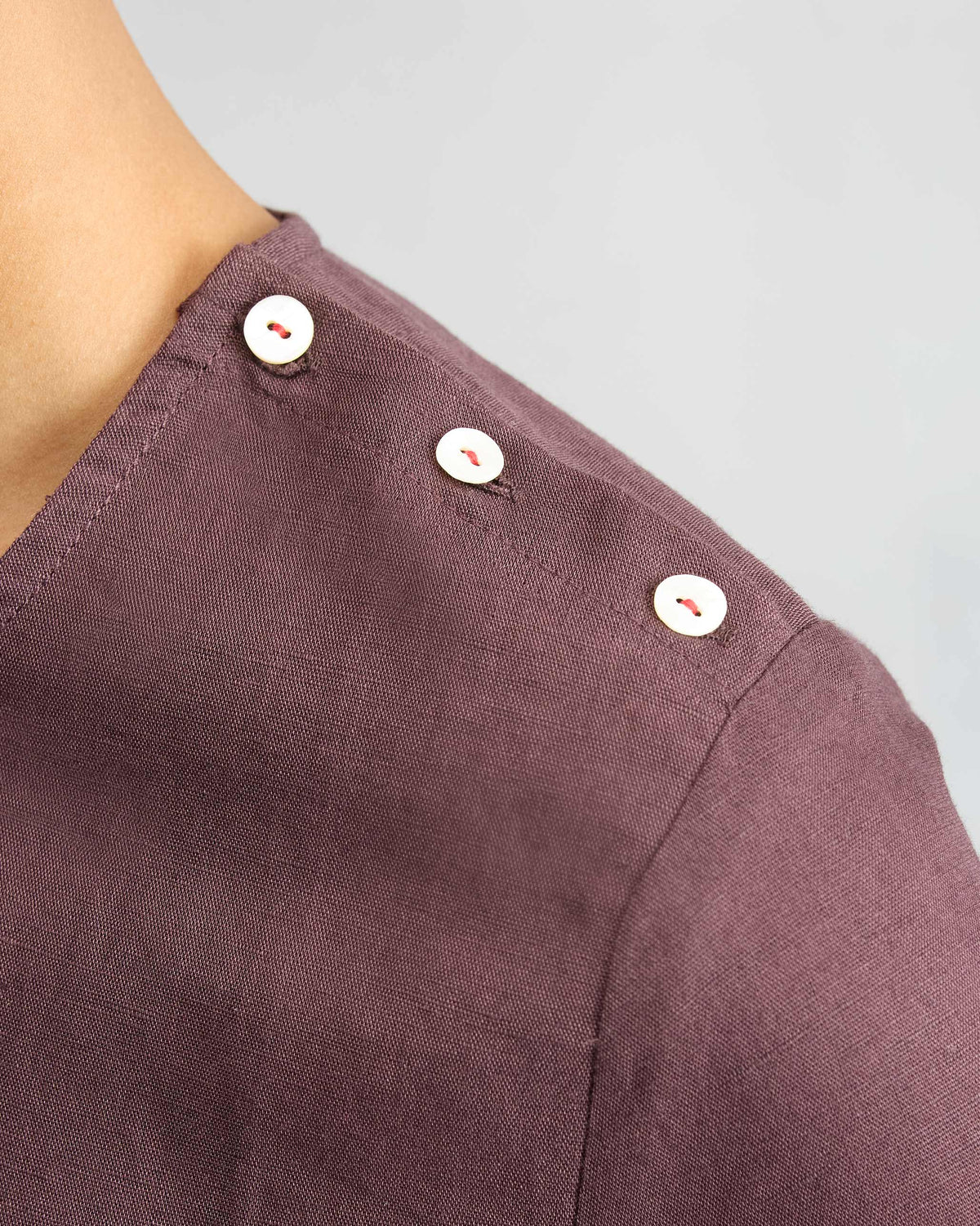 Close-up of a chocolate plum High Slit Top showing white shoulder buttons.