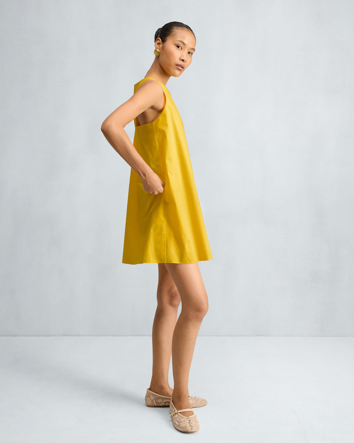 Side view of a yellow short racerback dress.