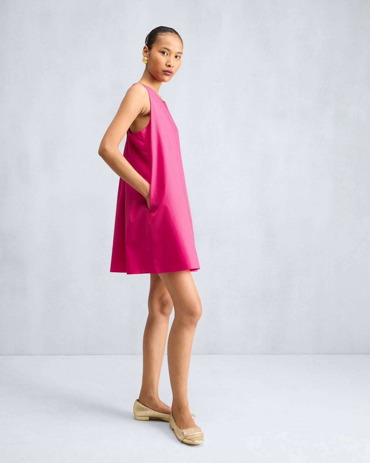 Side view of a fuchsia short racerback dress with a side pocket.