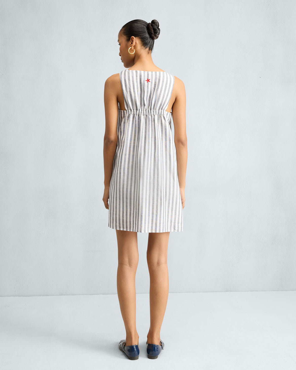 Back of a striped short racerback dress with an elastic mid-back gather and red star.