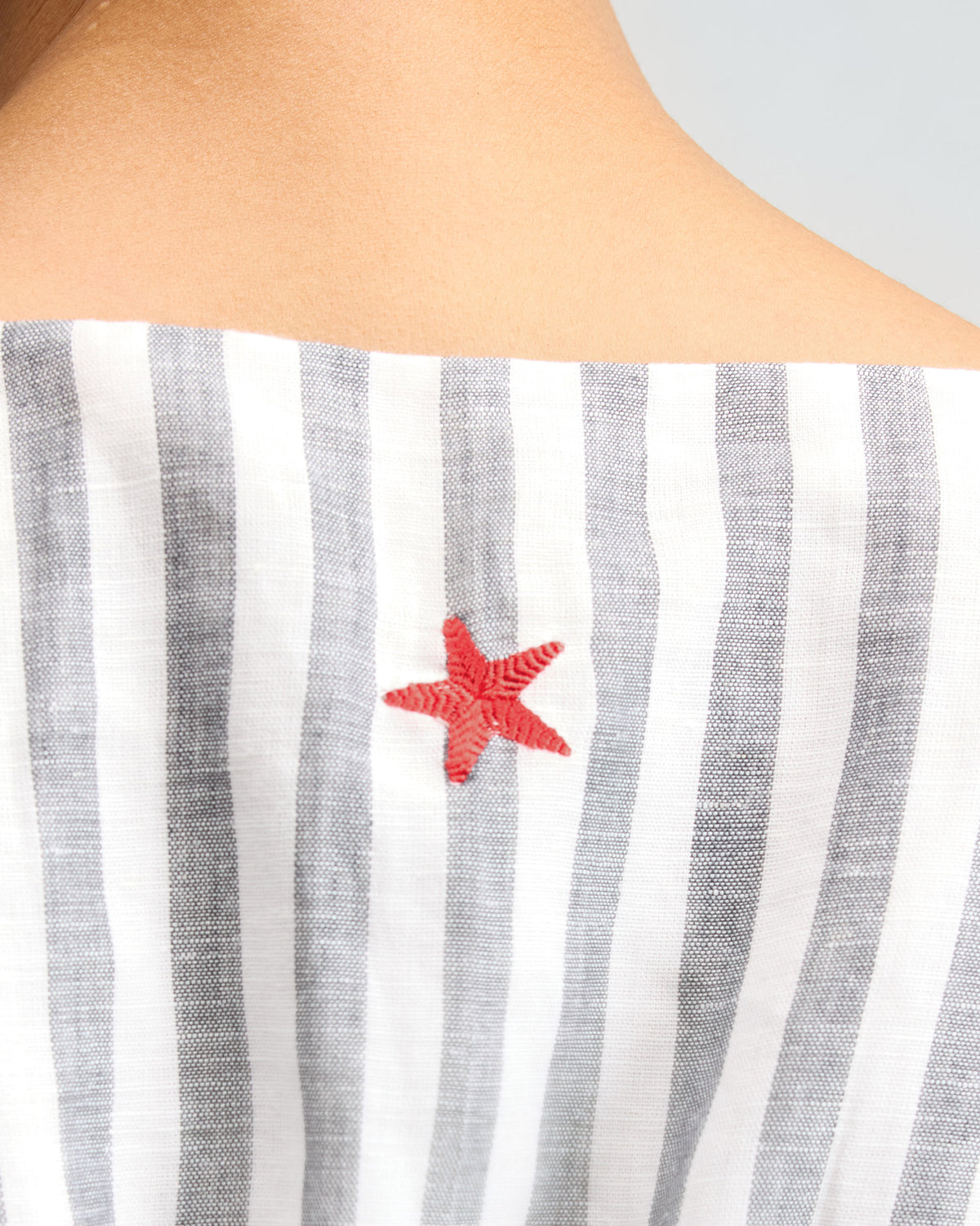 Close-up of a short racerback dress showing a red embroidered starfish at the neck.