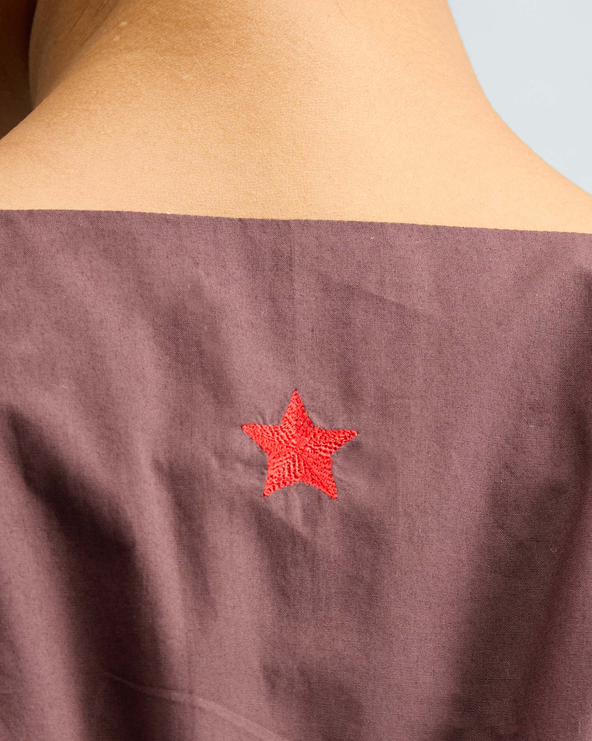 Close-up of a chocolate plum short racerback dress with a red star on the back.