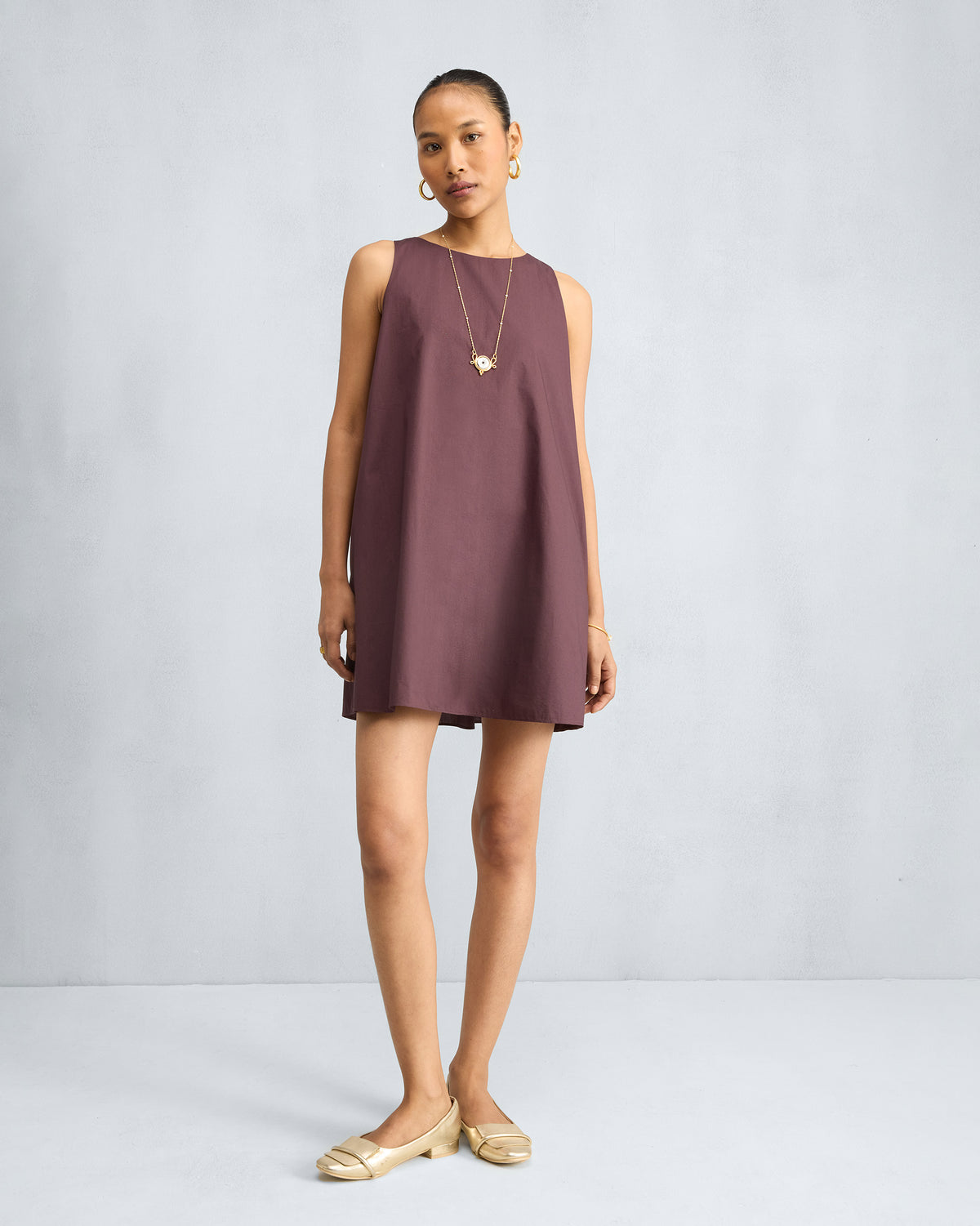 Person wearing a chocolate plum short racerback dress with a boat neck.