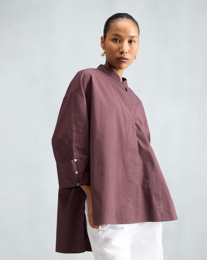Person wearing a chocolate plum Cirrus shirt with a high-low hem.