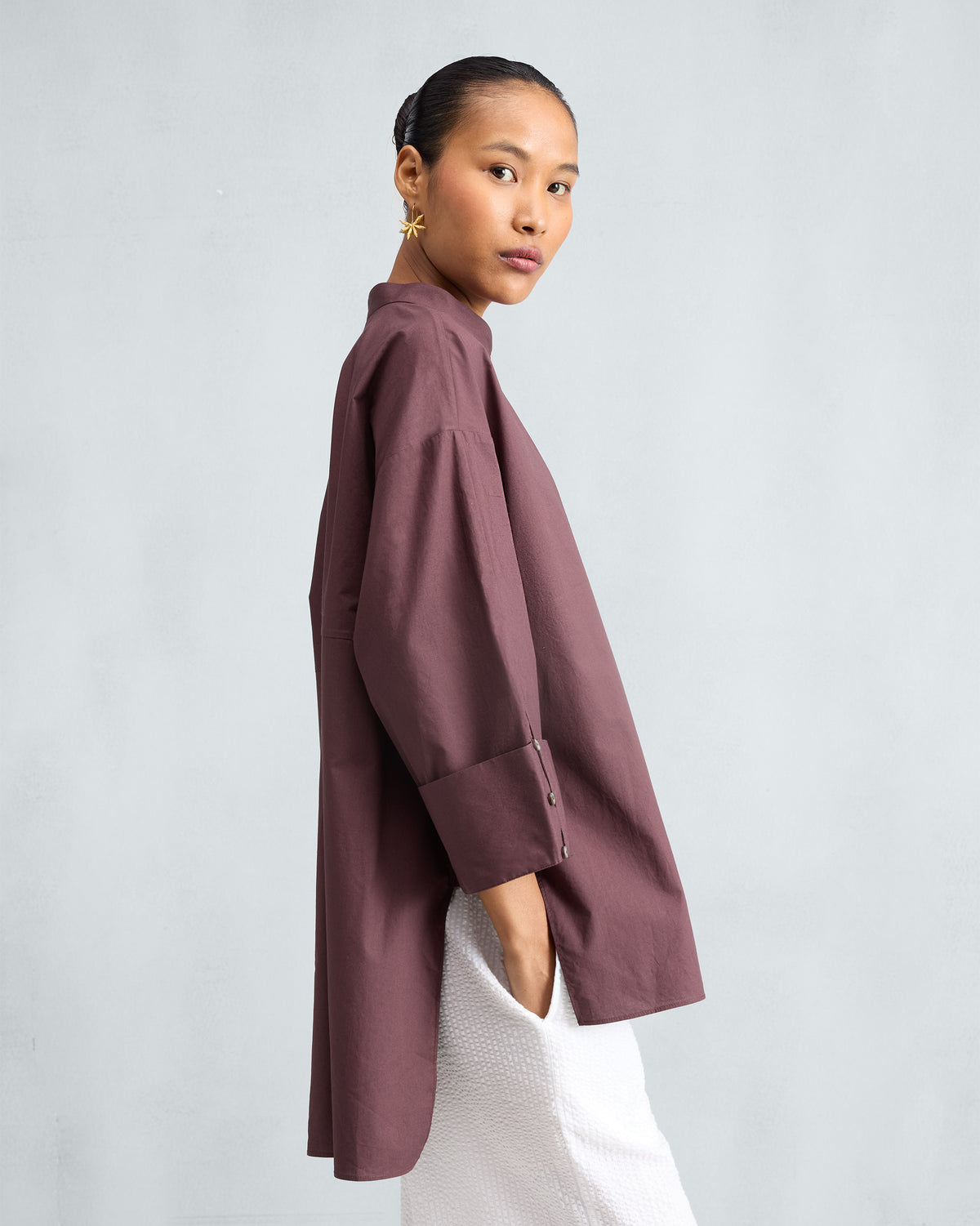 Side view of a chocolate plum Cirrus shirt with a deep side slit.