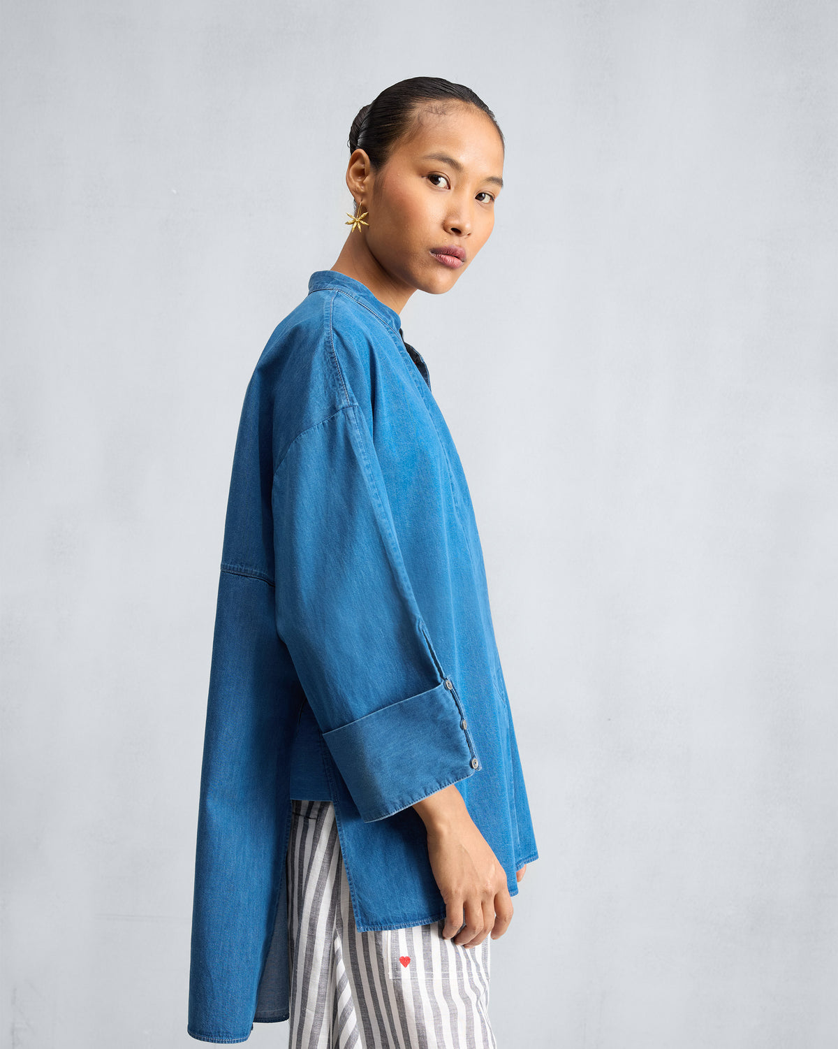 Side view of a blue denim Cirrus shirt with a long back hem.