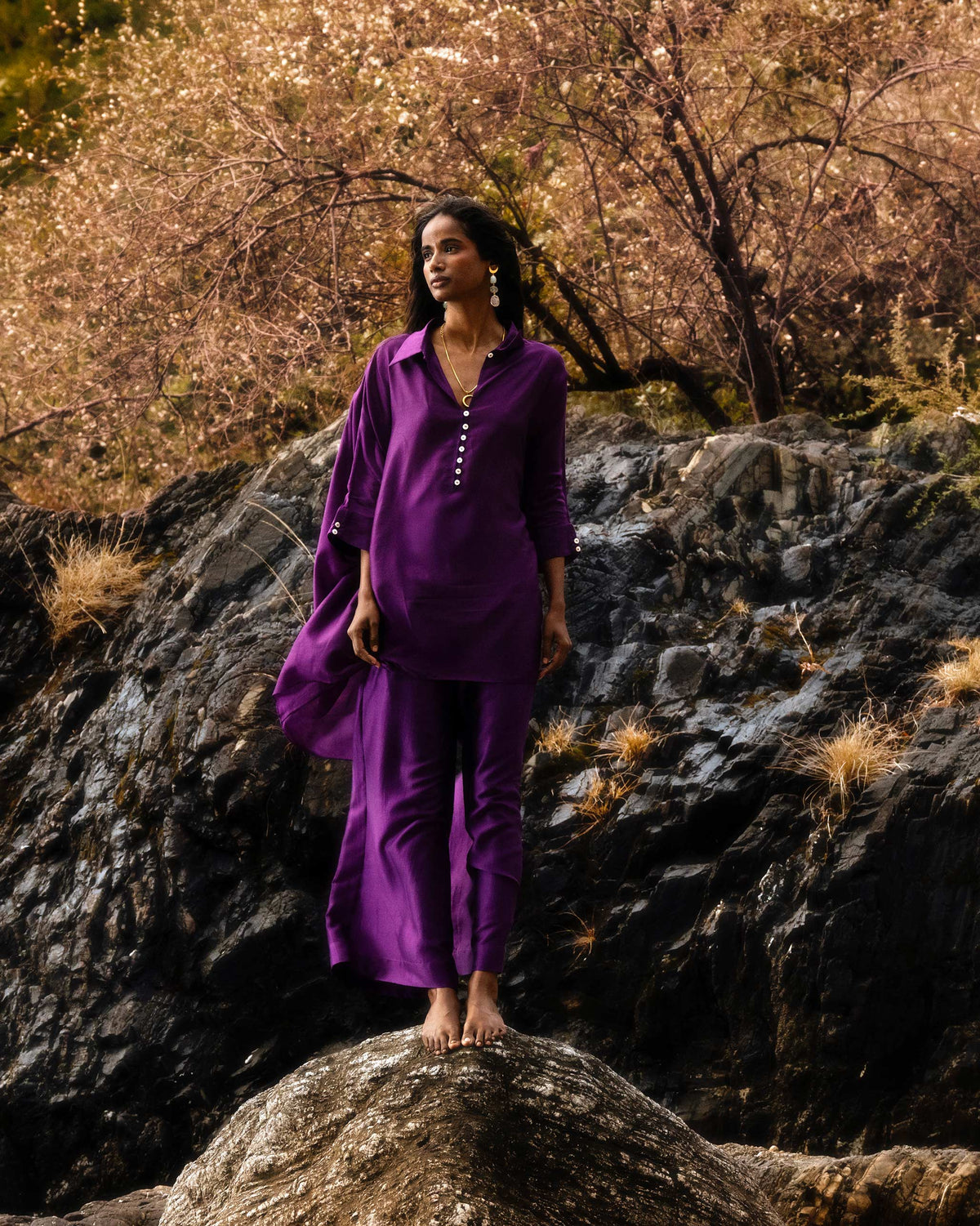 Person wearing a purple Hala Tunic with its sleeves rolled.