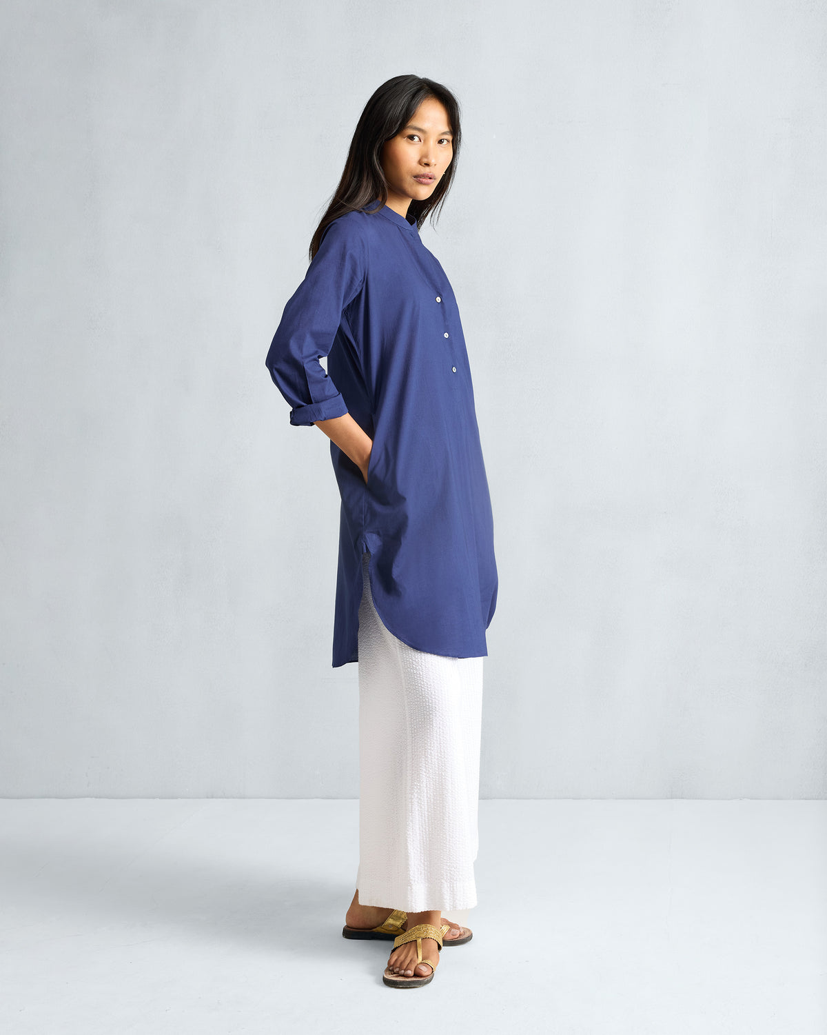 Side view of an ink blue mid-length kurta with a hip pocket and curved hem.