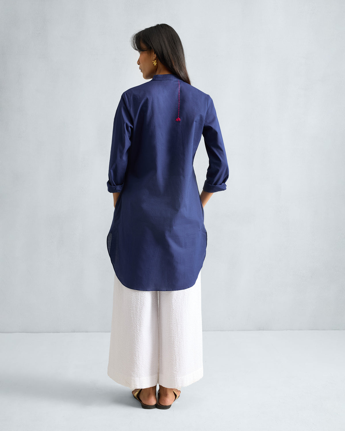 Back of an ink blue mid-length kurta with a pink embroidered elephant on the upper back.