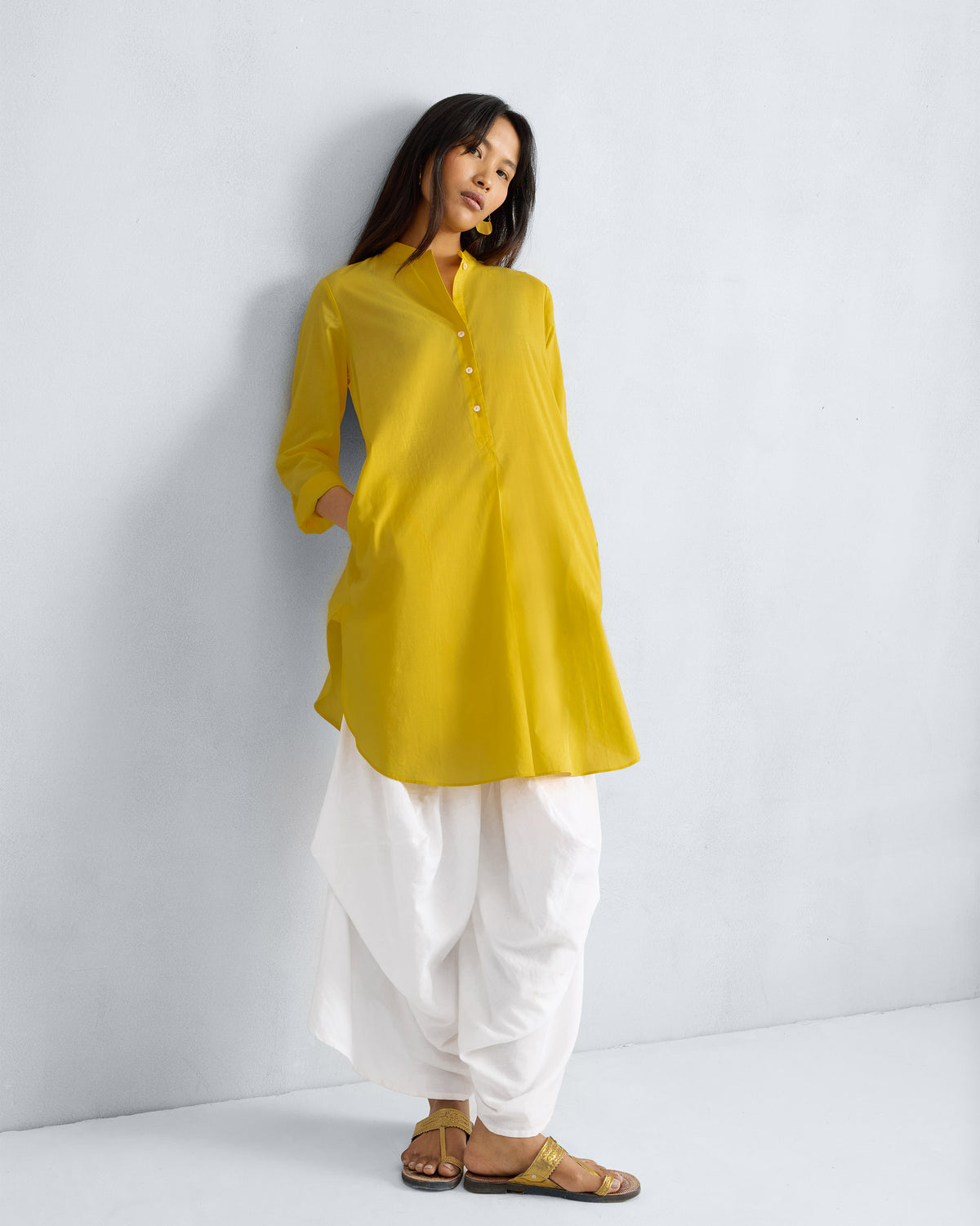 Person wearing a yellow mid-length kurta with a mandarin collar and side pocket.