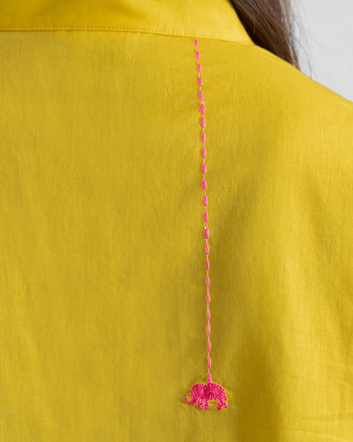 Close-up of a pink embroidered elephant on a yellow kurta.