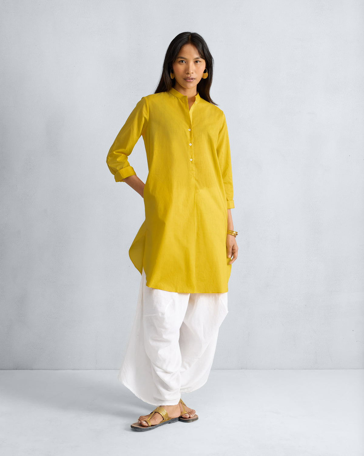 Person wearing a yellow mid-length kurta with a button placket and side pocket.