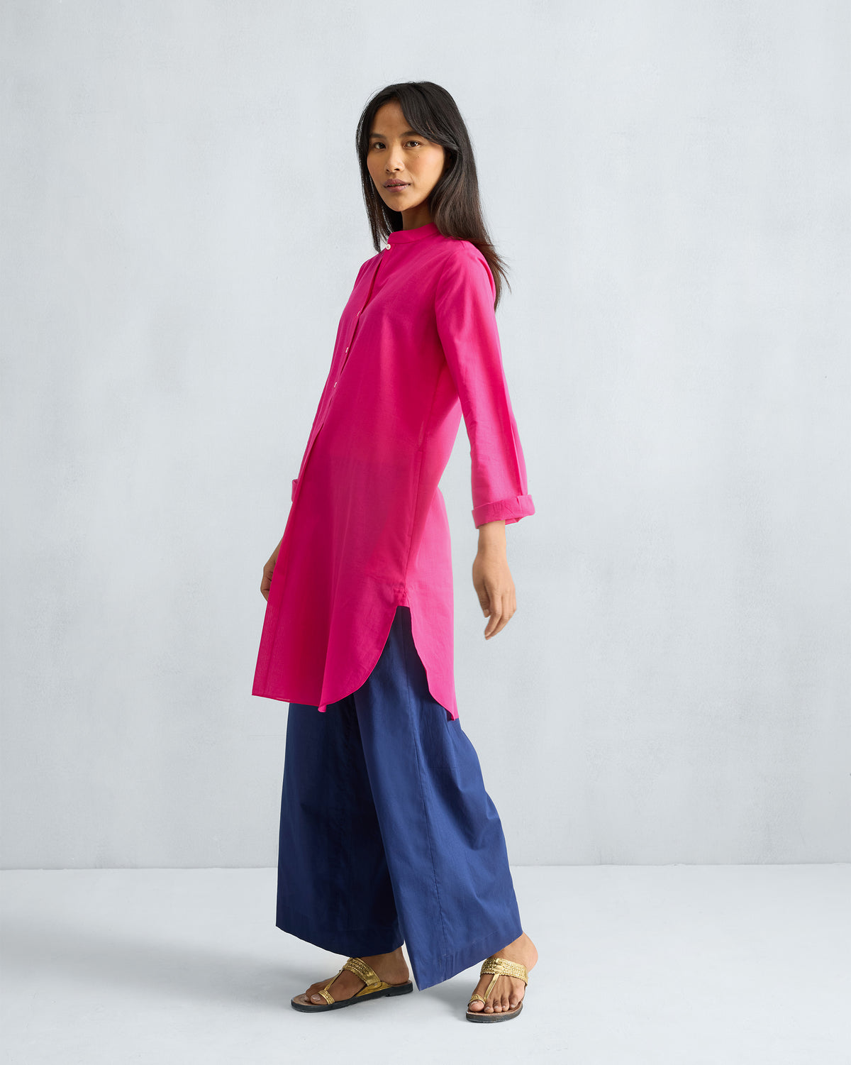 Side view of a fuchsia mid-length kurta with side slits and a curved hem.