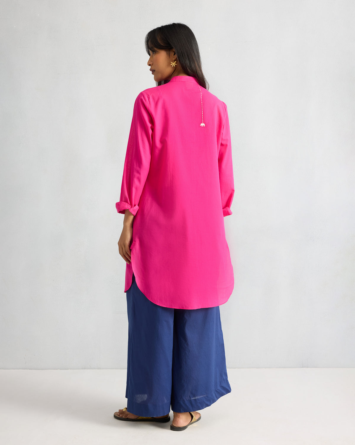 Back of a fuchsia mid-length kurta with a curved hem.