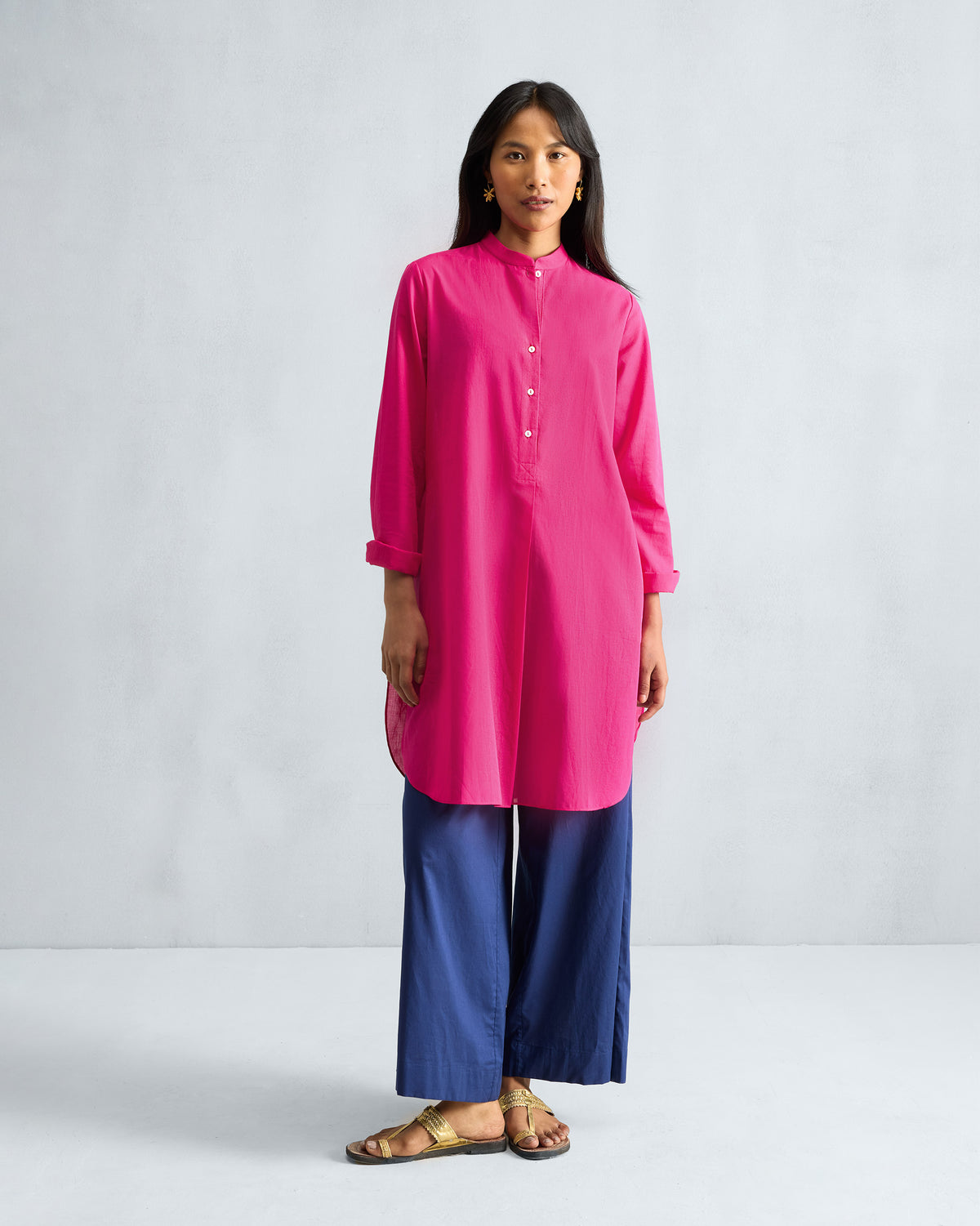 Person wearing a fuchsia mid-length kurta with a button placket and curved hem.